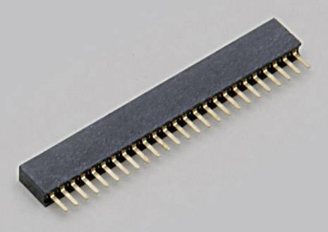 Un connecteur noir avec des broches métalliques dorées est posé sur une surface grise.