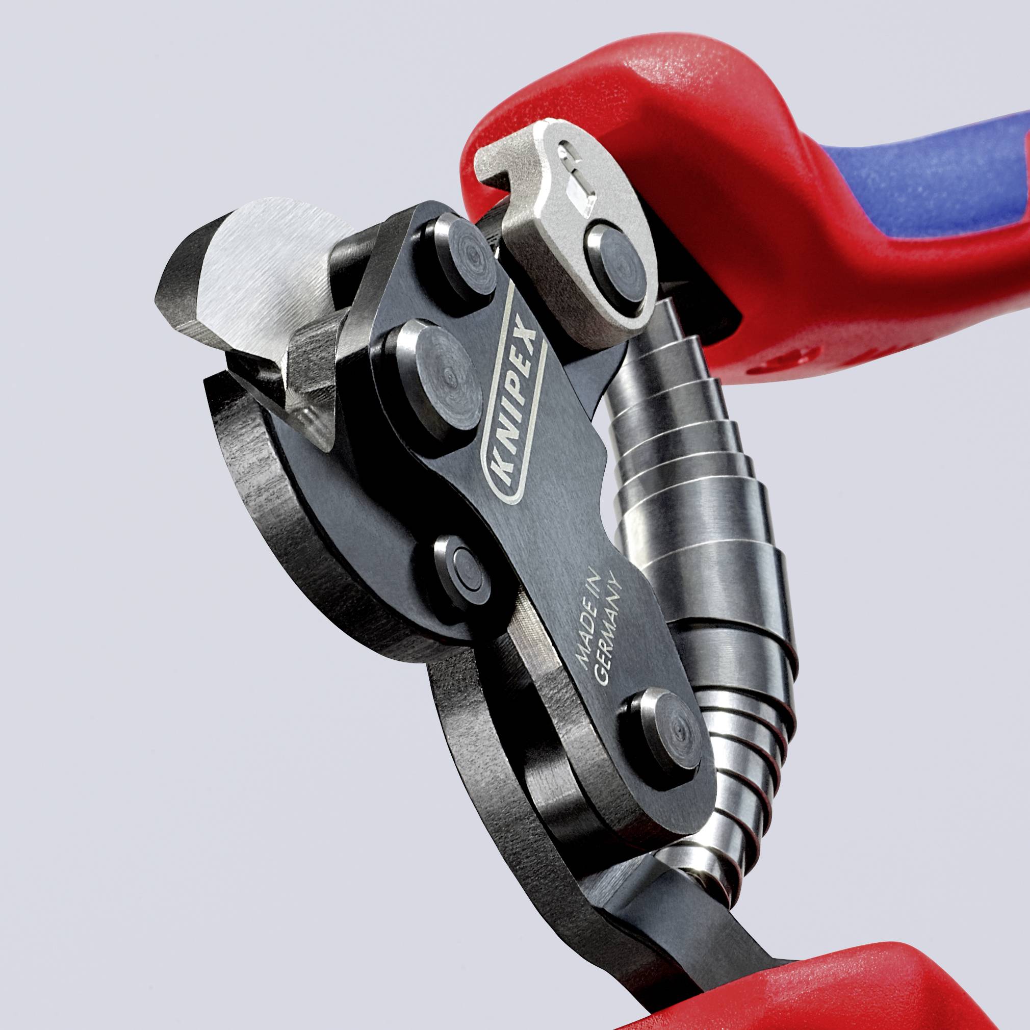 Pince avec poignée rouge, tête de coupe ouverte. Nom de marque 'KNIPEX' et 'Made in Germany' visibles sur l'outil.