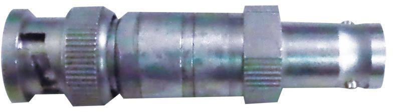 Un adaptateur métallique argenté, probablement un connecteur coaxial HF avec bord strié et boîtier cylindrique, est posé horizontalement.