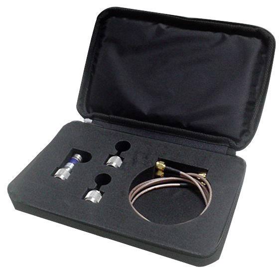 Un étui noir ouvert contient deux adaptateurs métalliques et un câble coaxial. Les adaptateurs et le câble sont logés dans des découpes adaptées à leur forme.