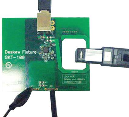 Carte verte portant l'inscription 'Deskew Fixture GKT-100' avec un périphérique USB noir connecté à la carte.