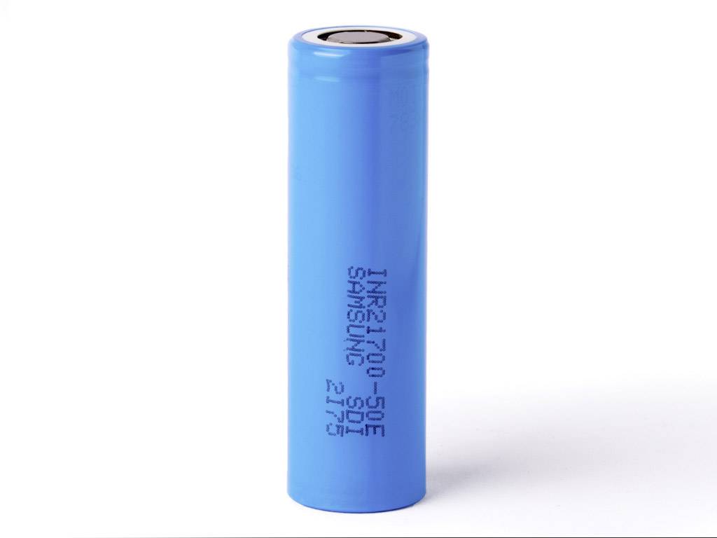 Une batterie lithium-ion cylindrique bleue portant l'inscription 'INR21700-50E SAMSUNG SDI' est posée verticalement sur une surface blanche.