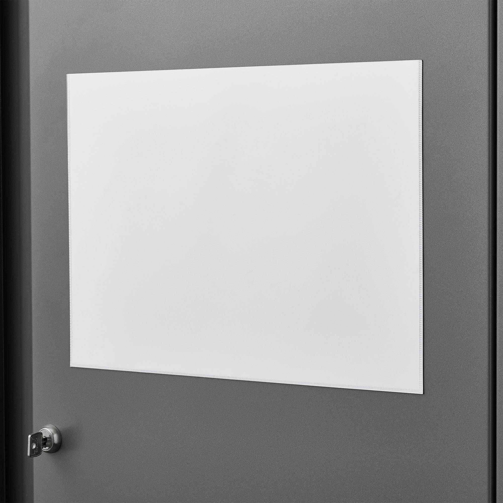 Un tableau blanc vierge est accroché à une porte grise avec une poignée à gauche, prêt à recevoir des notes ou des annonces.