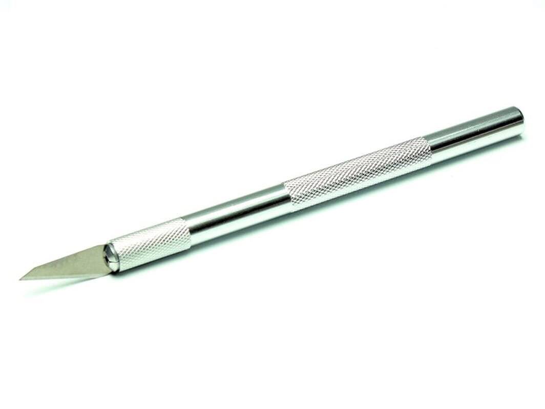 Un couteau de précision argenté avec une lame tranchante et biseautée et une poignée texturée repose sur un fond blanc.