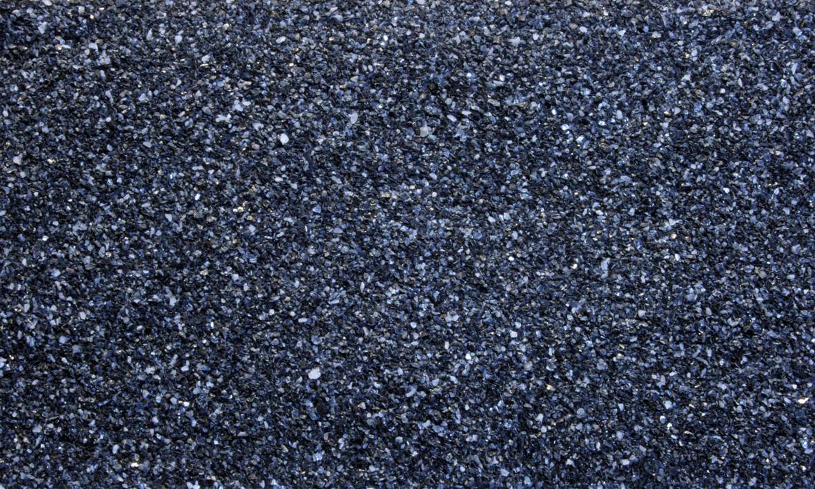 Gros plan sur une surface d'asphalte structurée de couleur gris foncé. La texture fine et granuleuse révèle une répartition uniforme de petites particules de pierre.