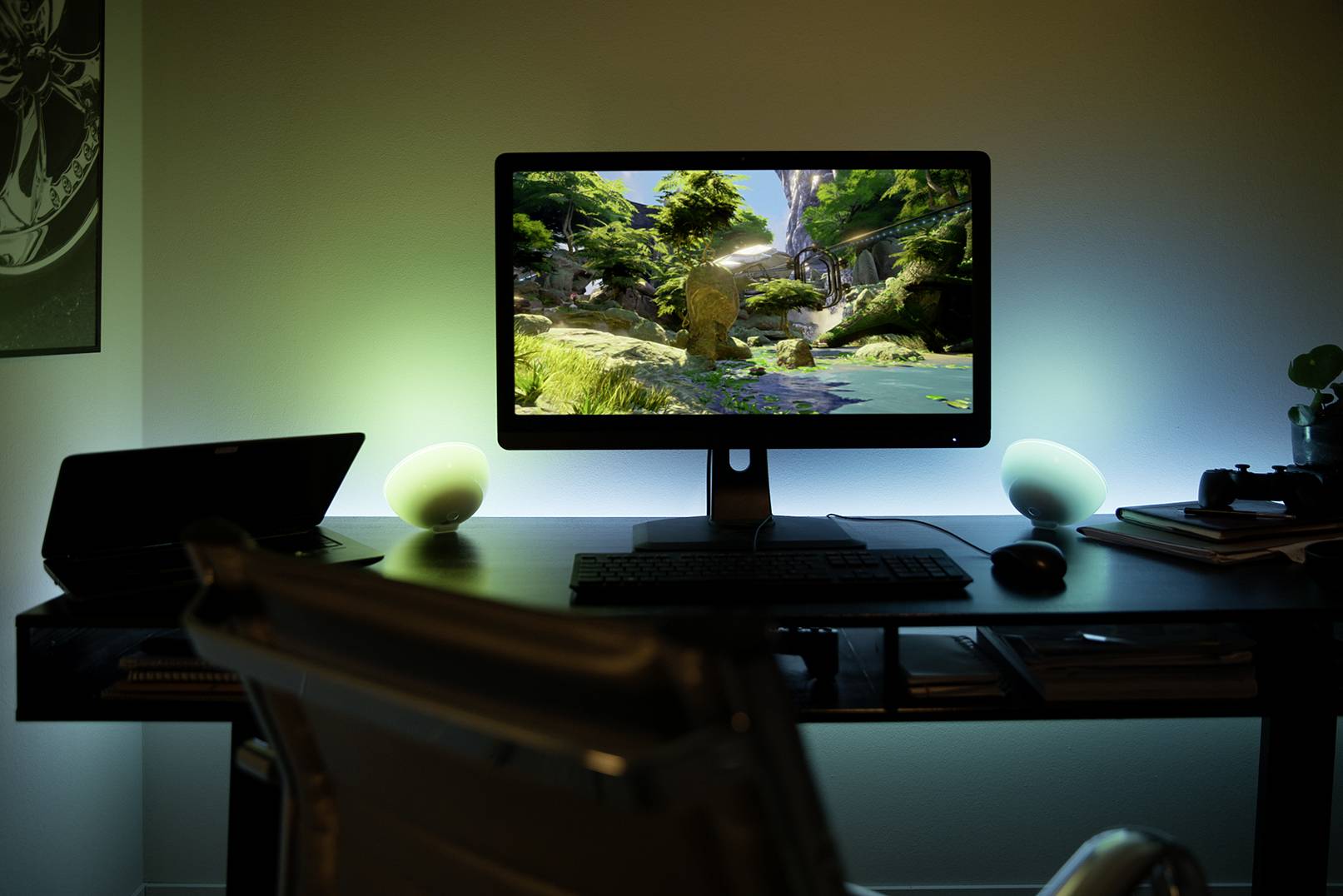 Un bureau avec un écran d'ordinateur affichant une scène de paysage. L'éclairage d'ambiance crée une atmosphère détendue.
