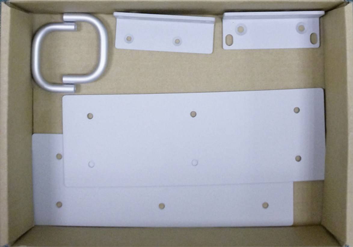 Une boîte en carton avec des garnitures métalliques, comprenant une poignée en forme de U et différentes plaques métalliques plates percées de trous.