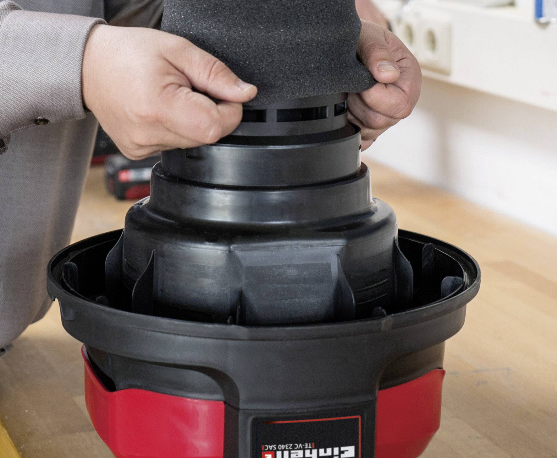 Une personne installe un filtre d'aspirateur sur une table dans un atelier.