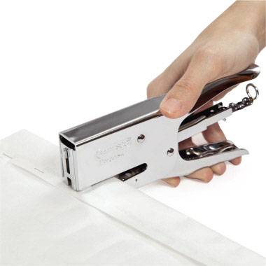 Une main utilise une agrafeuse pour fixer une feuille.