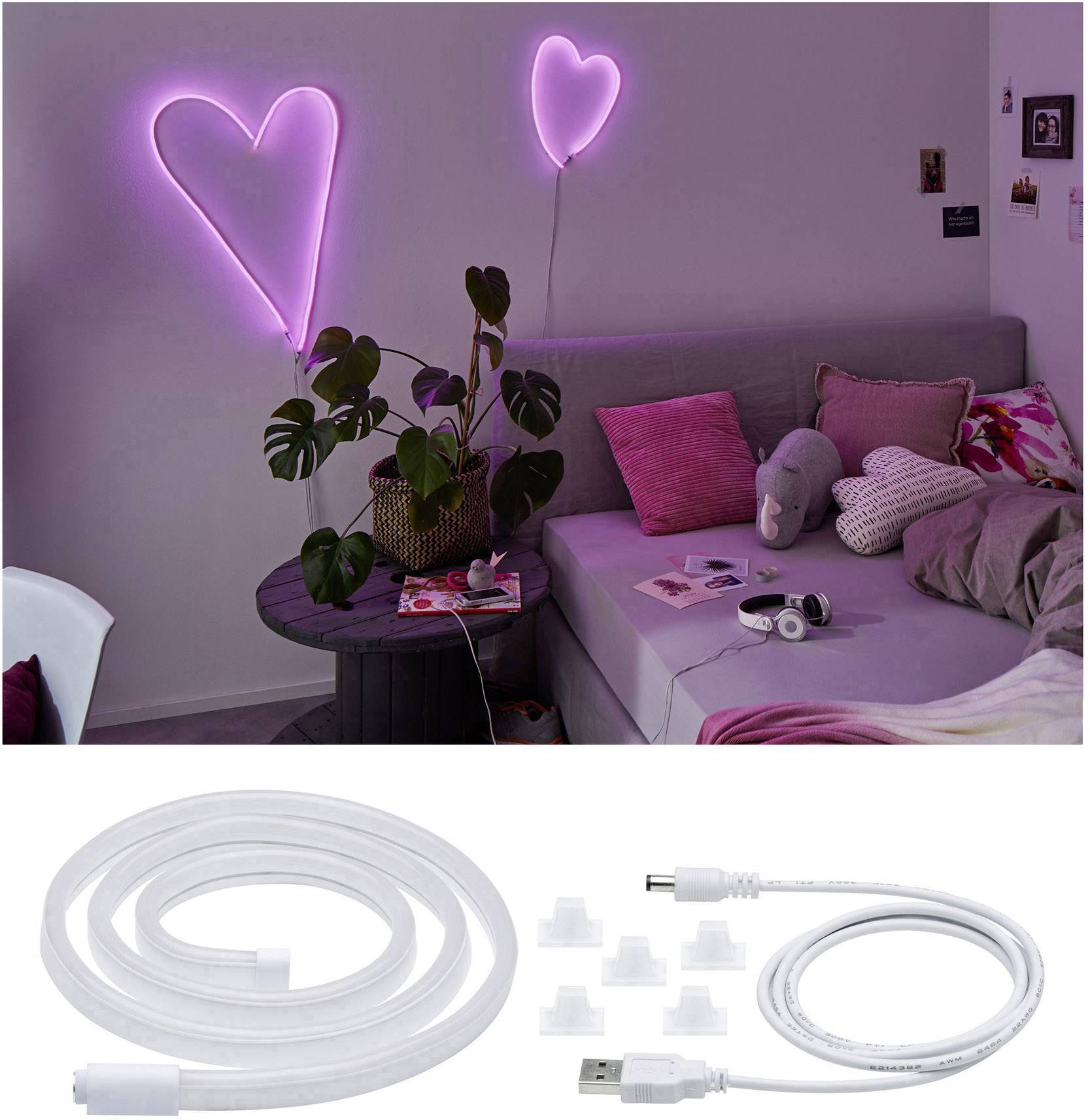 Un salon avec un canapé gris, décoré de coussins roses et d'écouteurs. Deux cœurs roses brillent sur le mur.