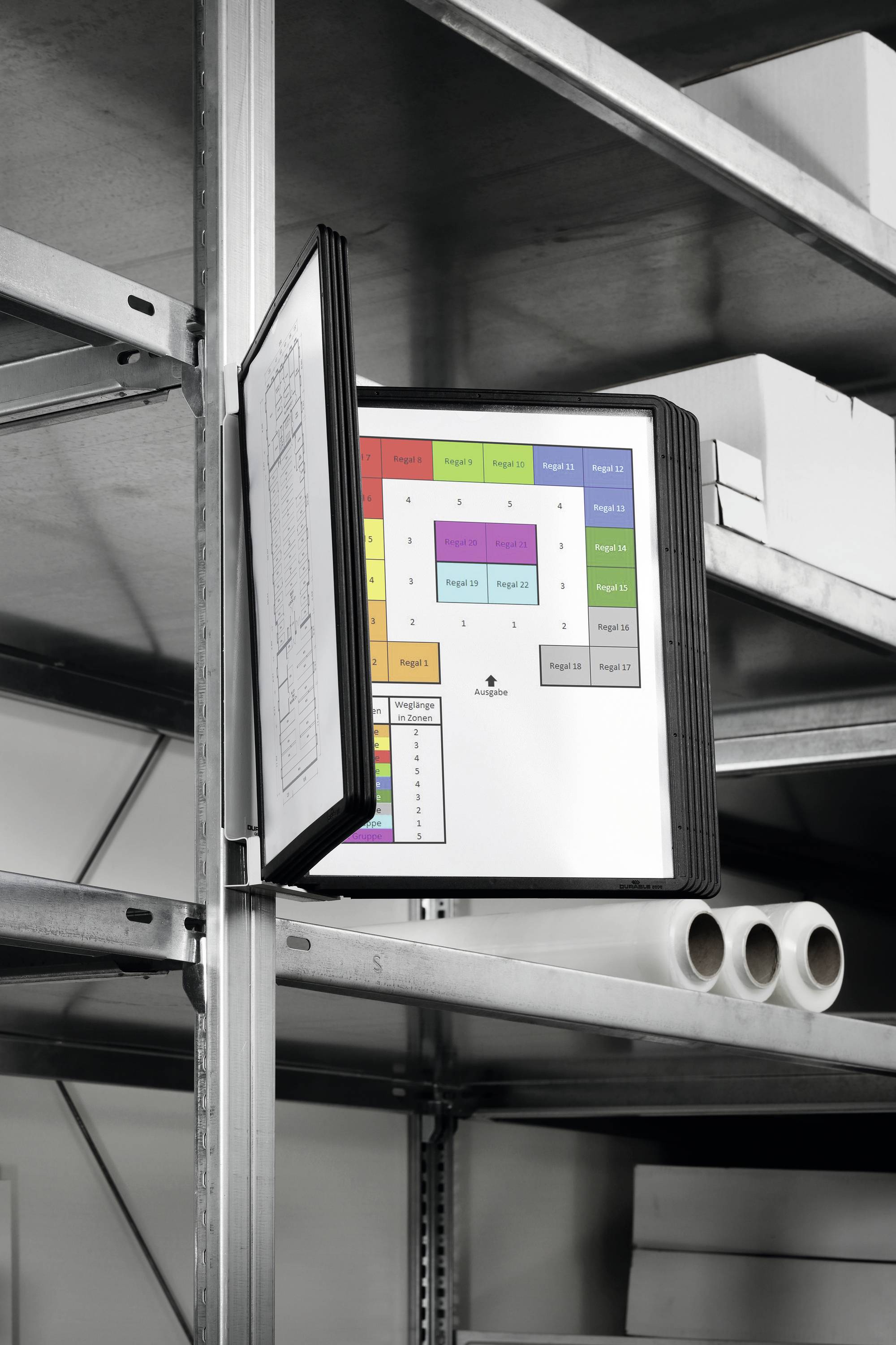 Un dossier ouvert avec des diagrammes colorés est suspendu dans une étagère. En dessous, plusieurs rouleaux de papier et des cartons sont posés.