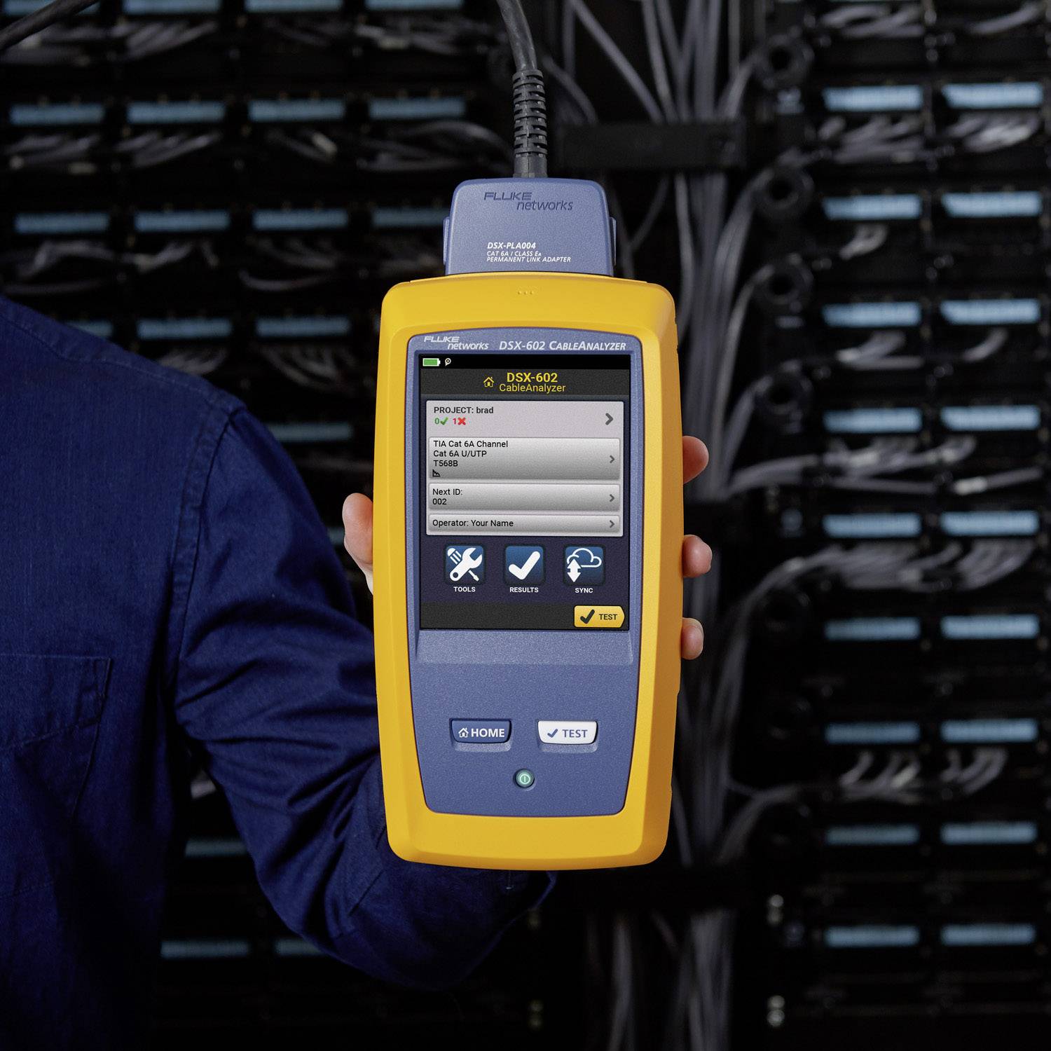 Un technicien tient un appareil de test de câbles jaune devant une armoire de serveurs. L'écran affiche des résultats de test et des options de détection de pannes.