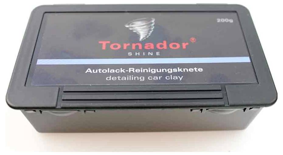 Conteneur rectangulaire noir étiqueté Tornador Shine argile de détail automobile, 200g. Bande bleue avec texte en allemand : Autolack-Reinigungsknete.