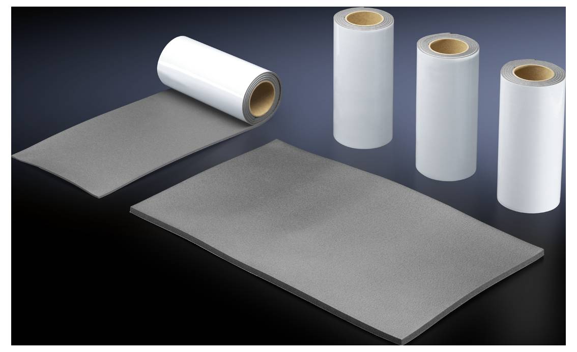 Plusieurs rouleaux de ruban adhésif et un morceau de matériau rectangulaire découpé sont posés sur un fond sombre.