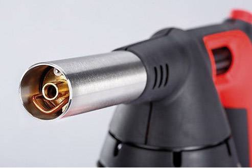 Un brûleur à gaz avec une buse métallique et une gâchette rouge, adapté aux applications de chauffage précis et aux travaux de soudure.