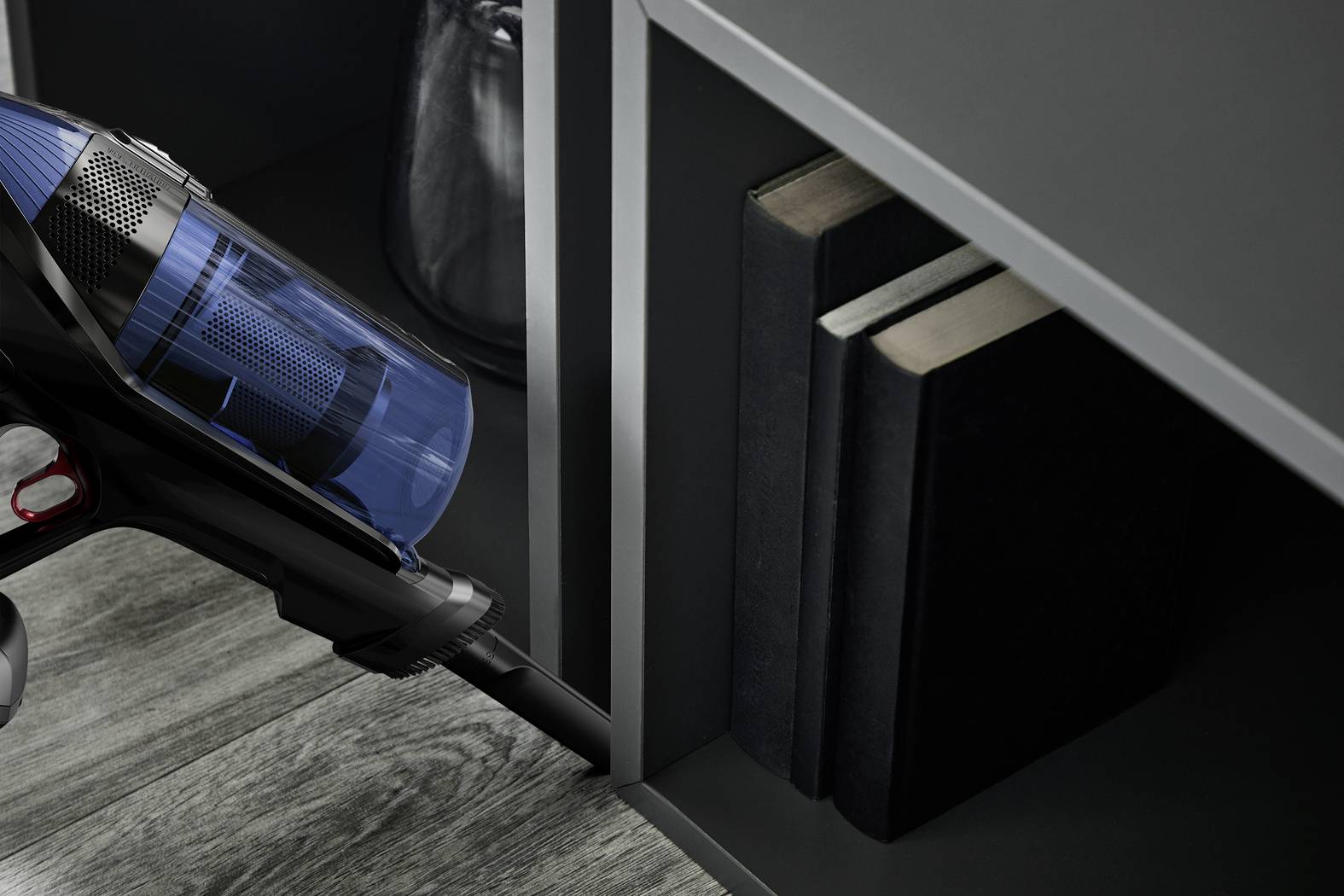 Un aspirateur à main nettoie les espaces étroits dans l'étagère à livres.