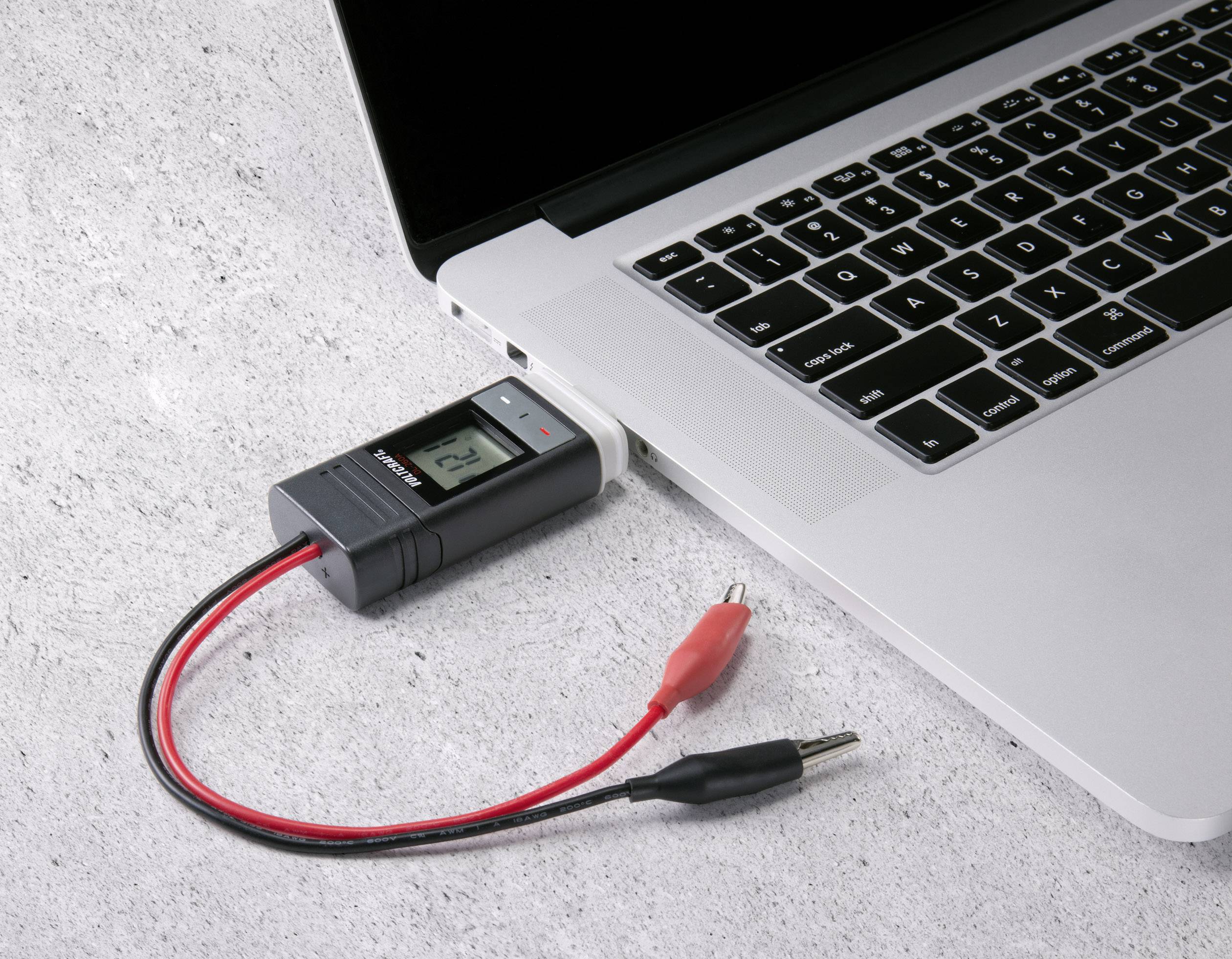 Un ordinateur portable avec un multimètre connecté via USB. Le multimètre affiche une valeur de 2,4.