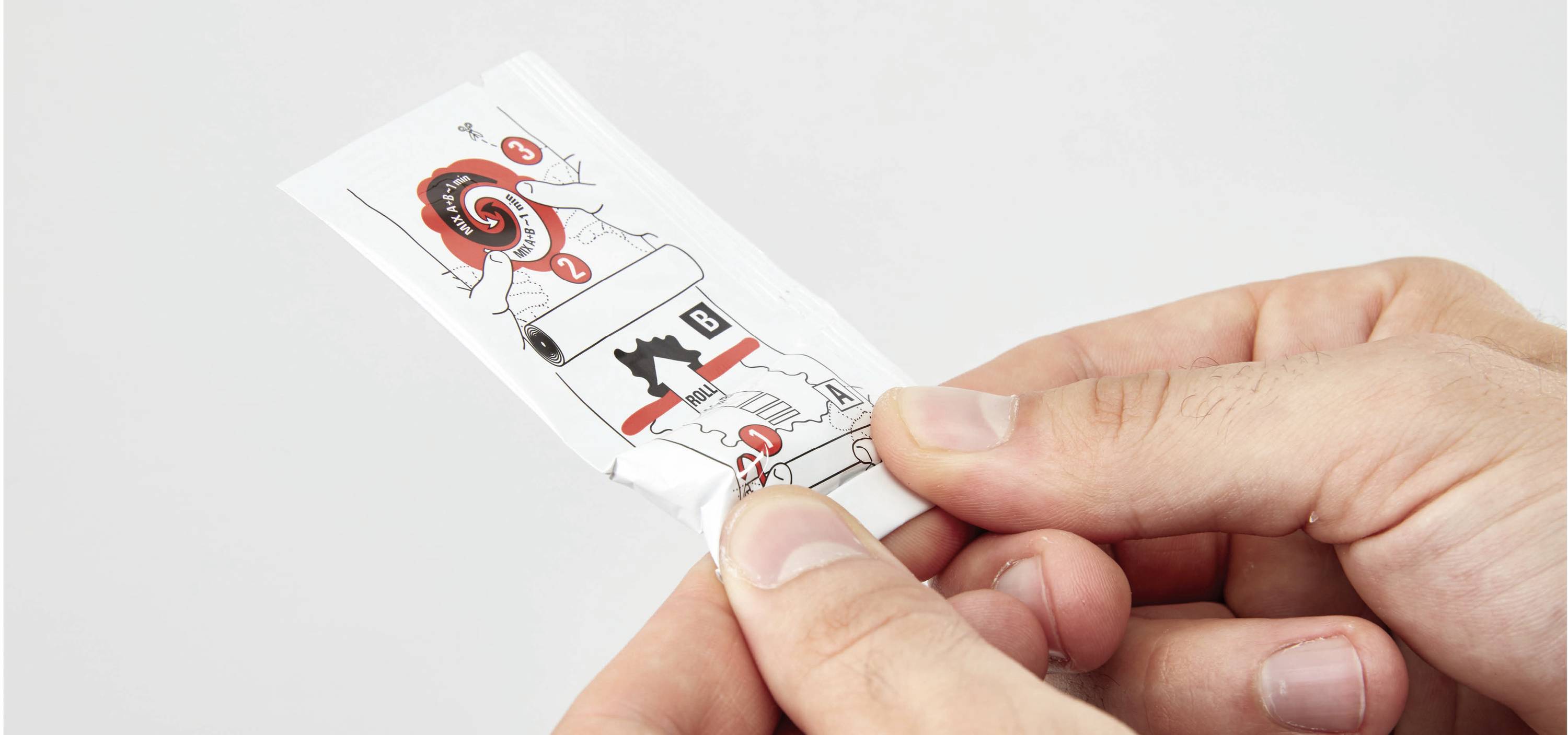 Une main tient une feuille avec un guide illustré pour rouler des cigarettes.