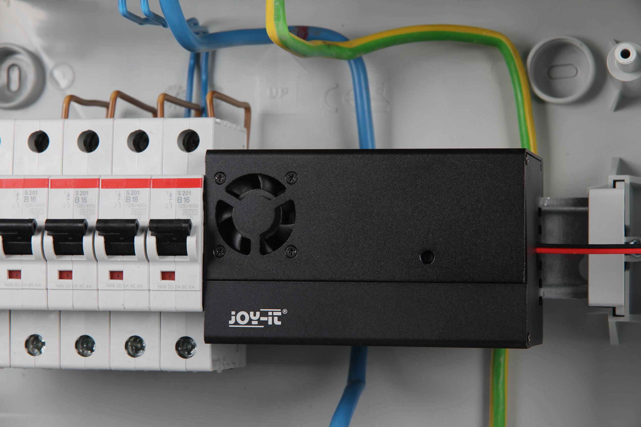 Boîte de distribution avec plusieurs interrupteurs et module de ventilation. Des câbles colorés relient les composants.