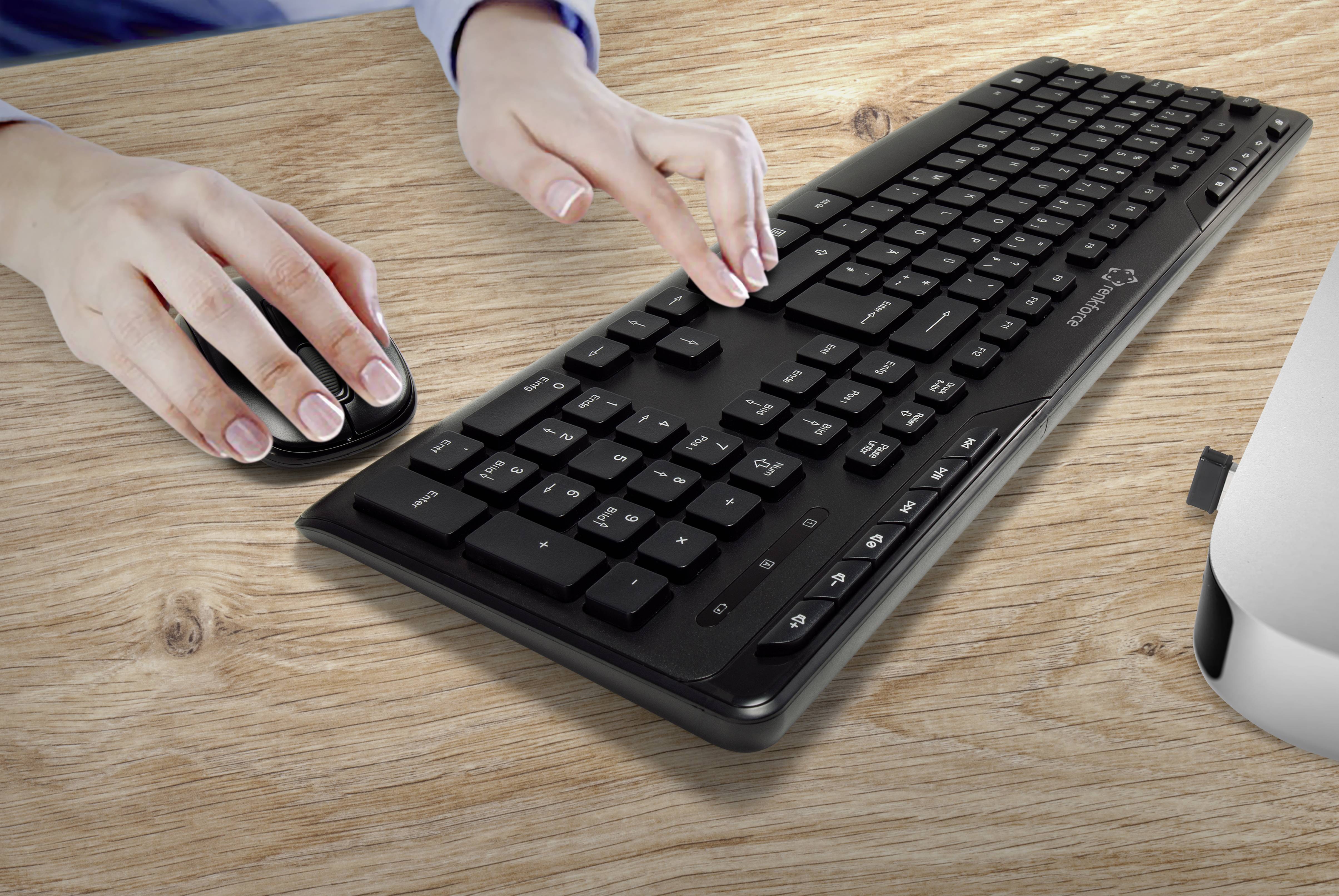 Mains d'une personne déplaçant une souris et tapant sur un clavier. La scène se déroule sur un bureau en bois.