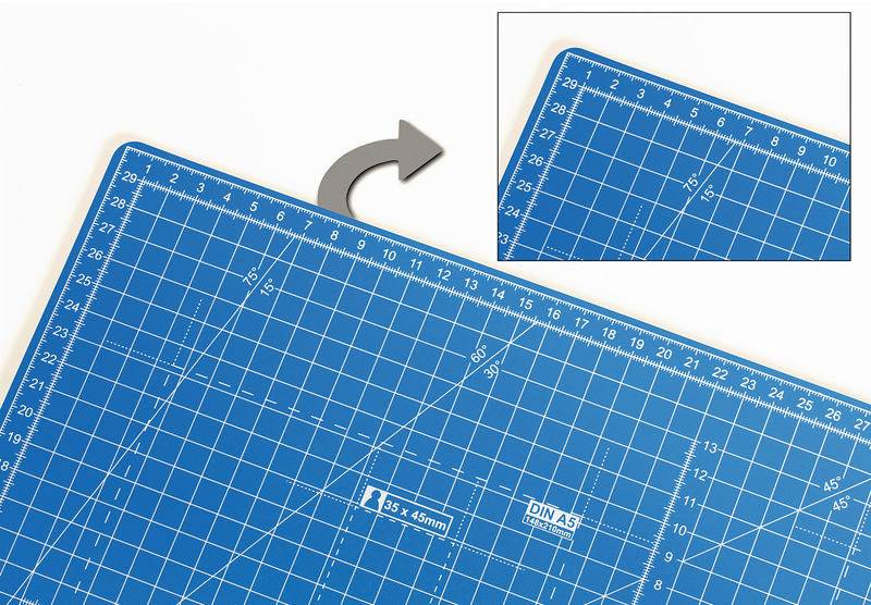 Tapis de coupe bleu avec grille quadrillée et échelles en centimètres et en pouces. Une flèche pointe vers un agrandissement du coin supérieur.