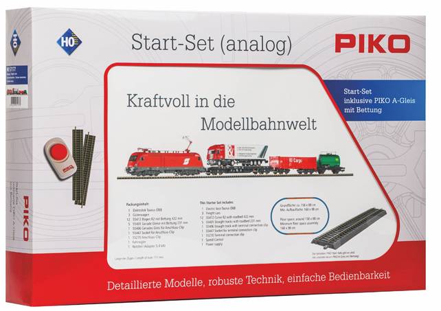 Boîte de kit de train modèle 'Start-Set (analogique)' présentant un train rouge, des éléments de voie ferrée et le texte 'Kraftvoll in die Modellbahnwelt.' [Puissamment dans le monde du modélisme ferroviaire.]