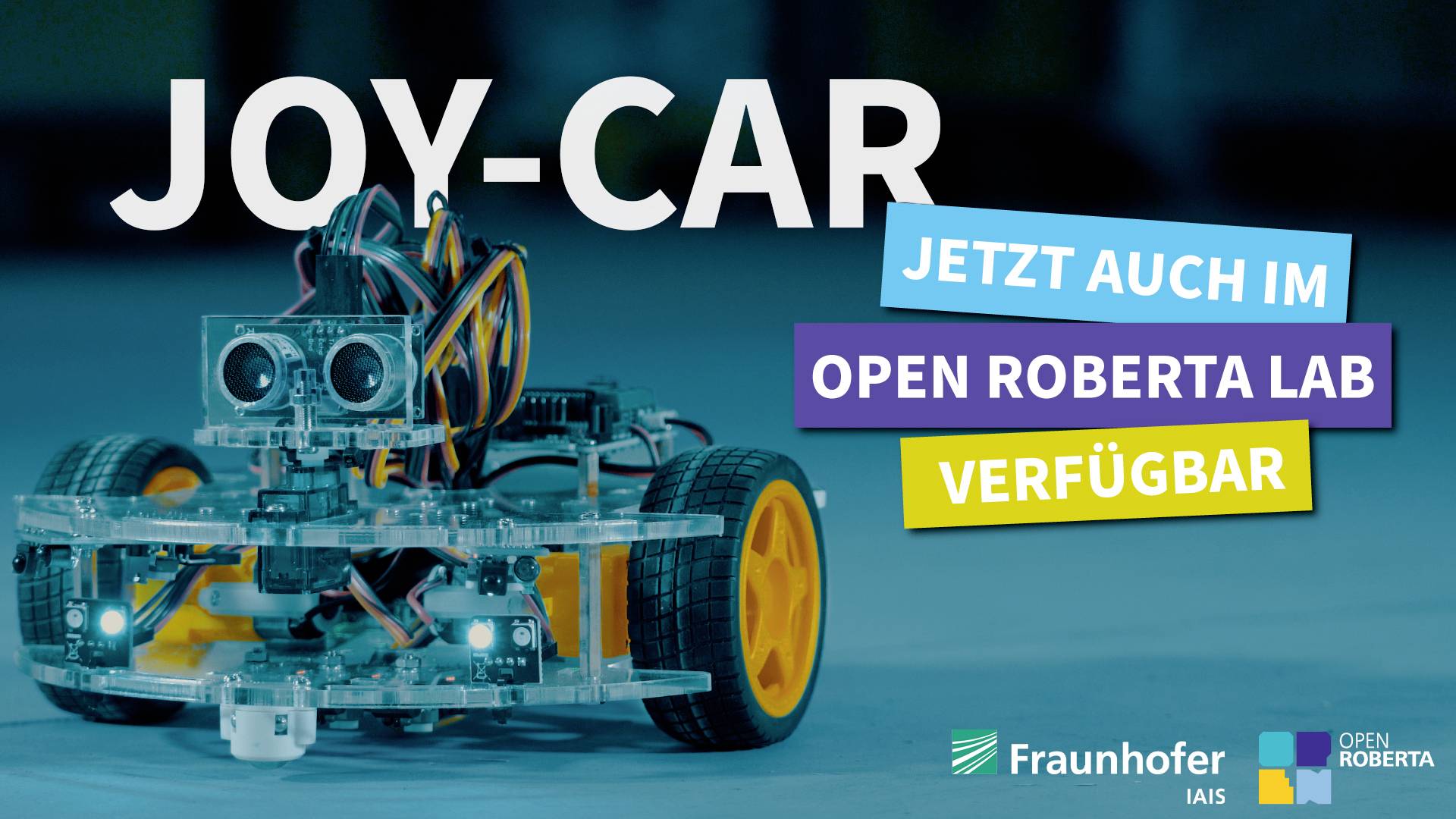 Voiture robotisée avec des capteurs, Texte : 'JOY-CAR maintenant aussi disponible dans le Open Roberta Lab'. Logos de Fraunhofer et Open Roberta.