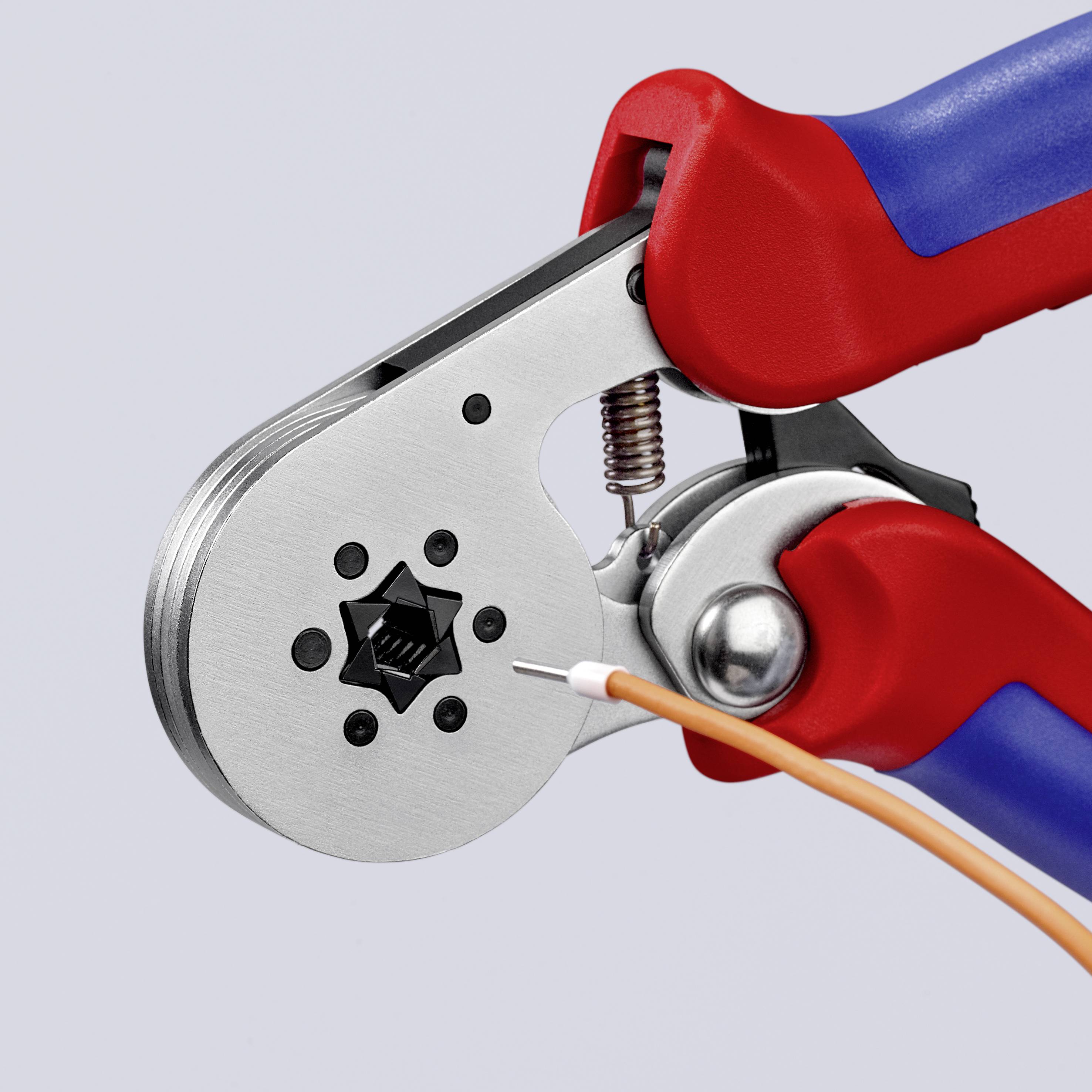 Une pince à sertir rouge et bleue comprime un connecteur métallique sur un câble orange. Outil pour installation électrique.