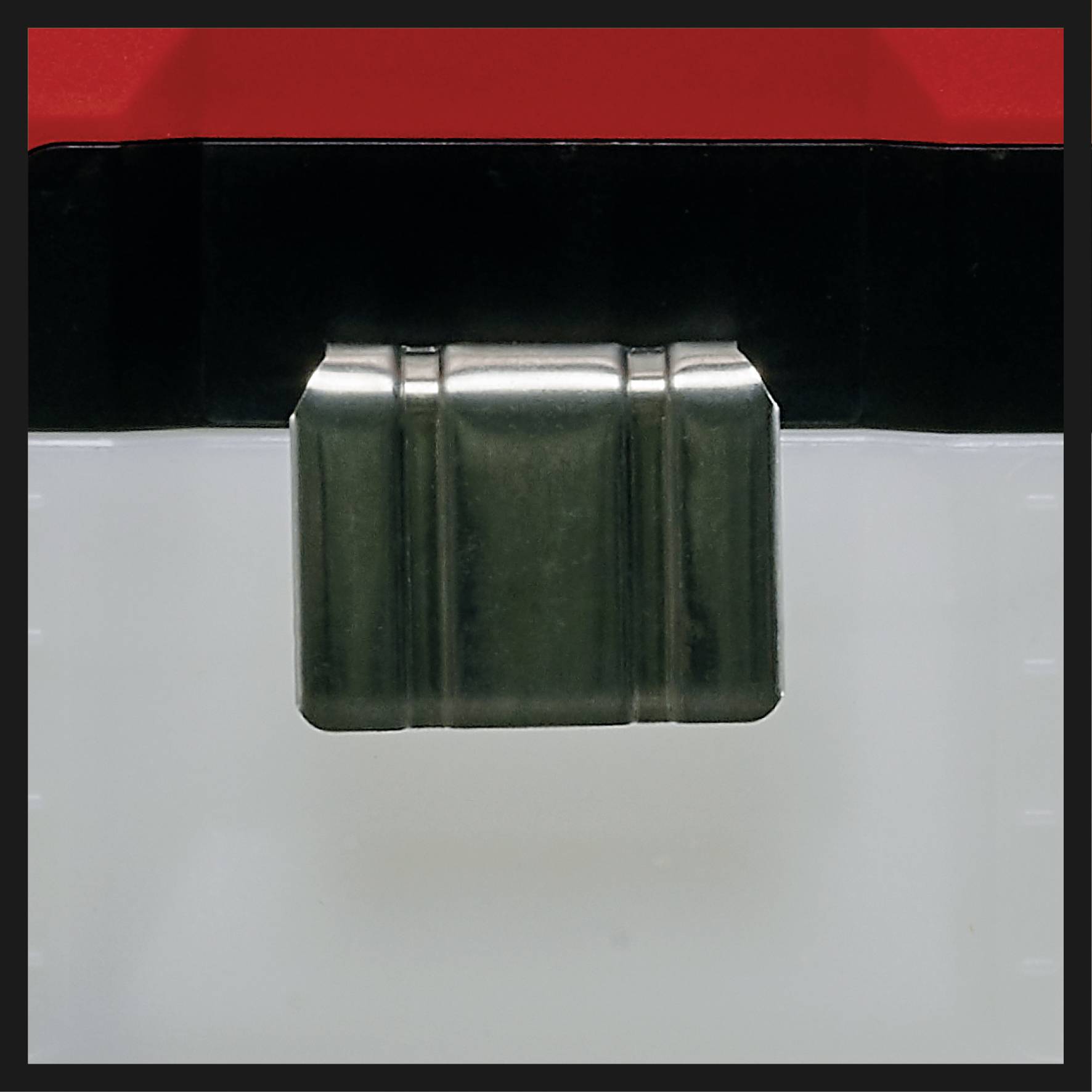 Un récipient en plastique transparent avec un couvercle noir et rouge. Un clip métallique fixe le couvercle au récipient.