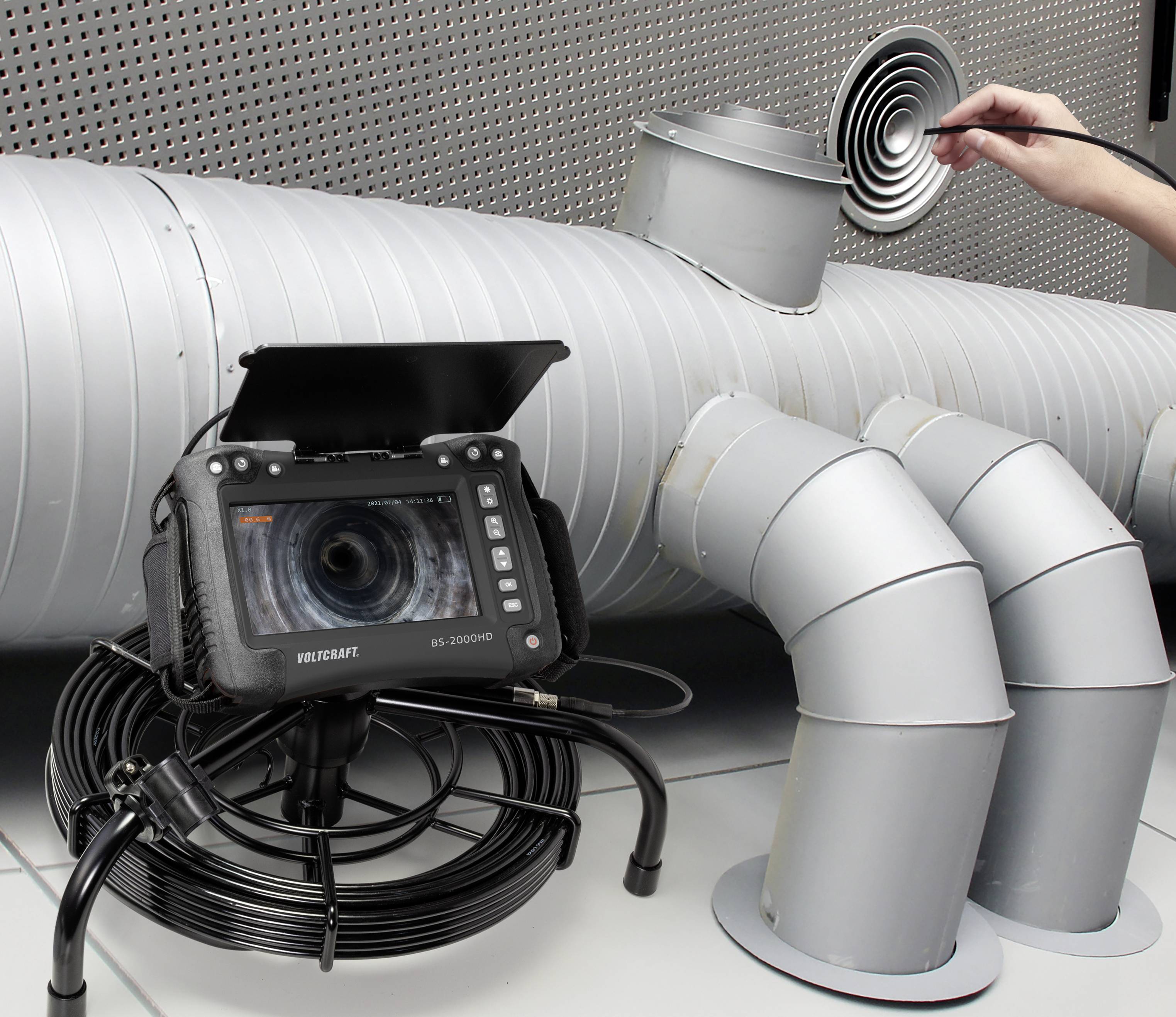 Une caméra d'inspection examine l'intérieur d'un système de ventilation. Une personne retire le couvercle. L'appareil affiche une vue en direct de l'intérieur.