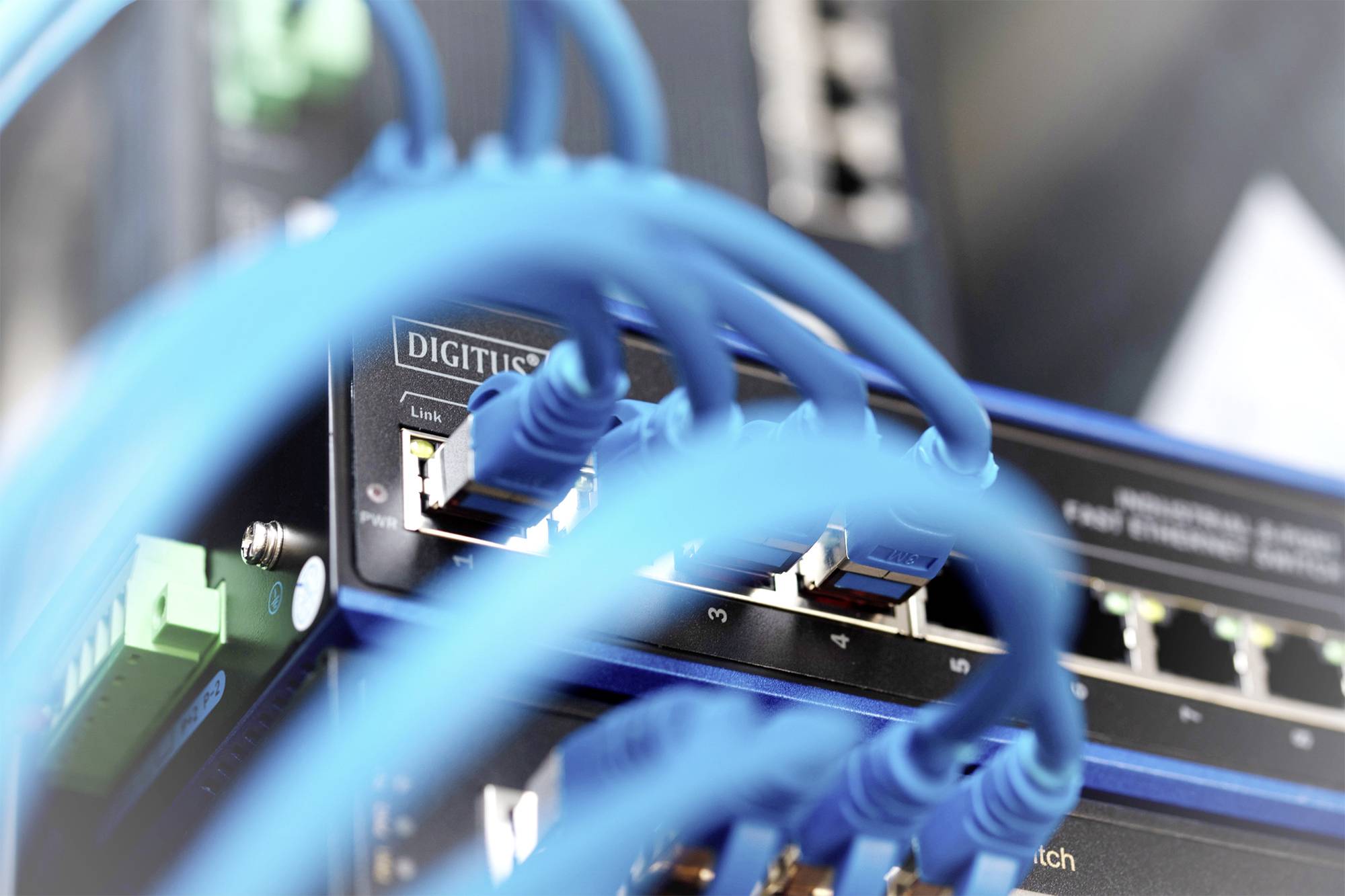 Un commutateur réseau avec plusieurs câbles Ethernet bleus connectés, offrant une connectivité pour différents appareils dans un réseau.