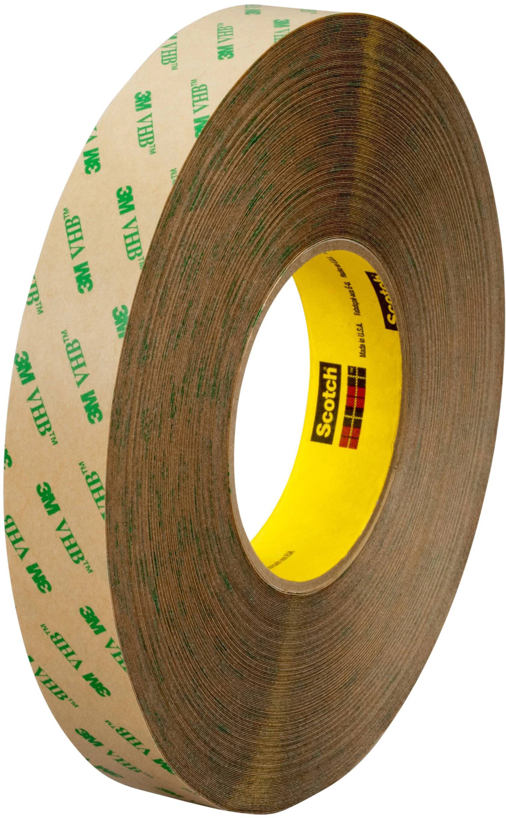 Un rouleau de ruban adhésif double face de la marque 3M VHB, réputé pour sa forte adhérence, avec un noyau jaune et un revêtement extérieur brun.