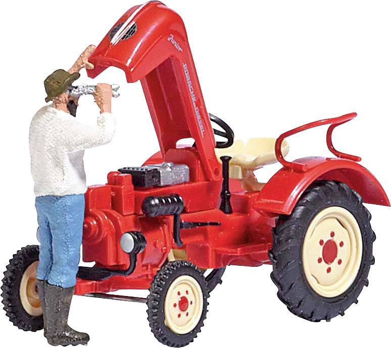 Figurine miniature d'un homme réparant un tracteur rouge avec le capot moteur relevé. L'homme porte des bottes et un chapeau.