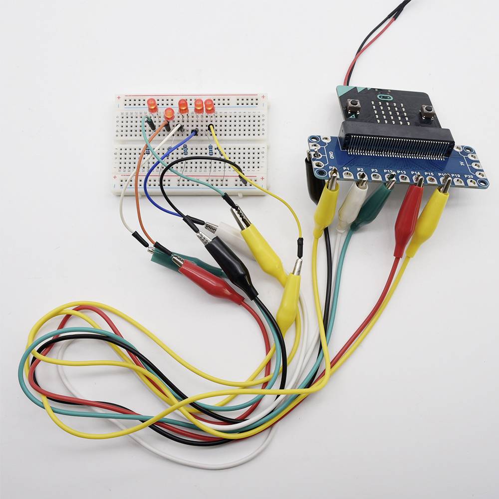 Un tableau de bord avec des LED est connecté à une carte de développement via plusieurs câbles. Le circuit démontre une connexion électronique.