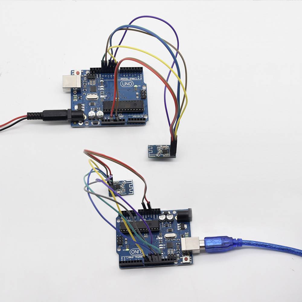 Deux cartes Arduino sont connectées par des câbles et des modules enfichables, sur un fond blanc. L'une d'entre elles est branchée via USB.