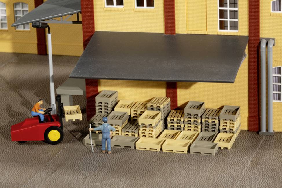 Entrepôt avec un chariot élévateur et deux personnes. Le chariot élévateur soulève une palette. Plusieurs palettes sont empilées.