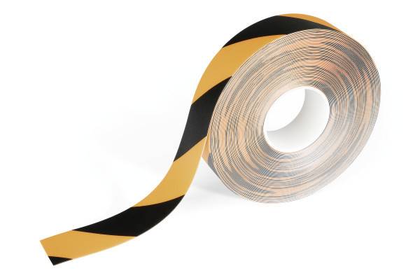 Un rouleau de ruban de signalisation à rayures diagonales jaunes et noires, souvent utilisé pour marquer ou délimiter des zones de danger.