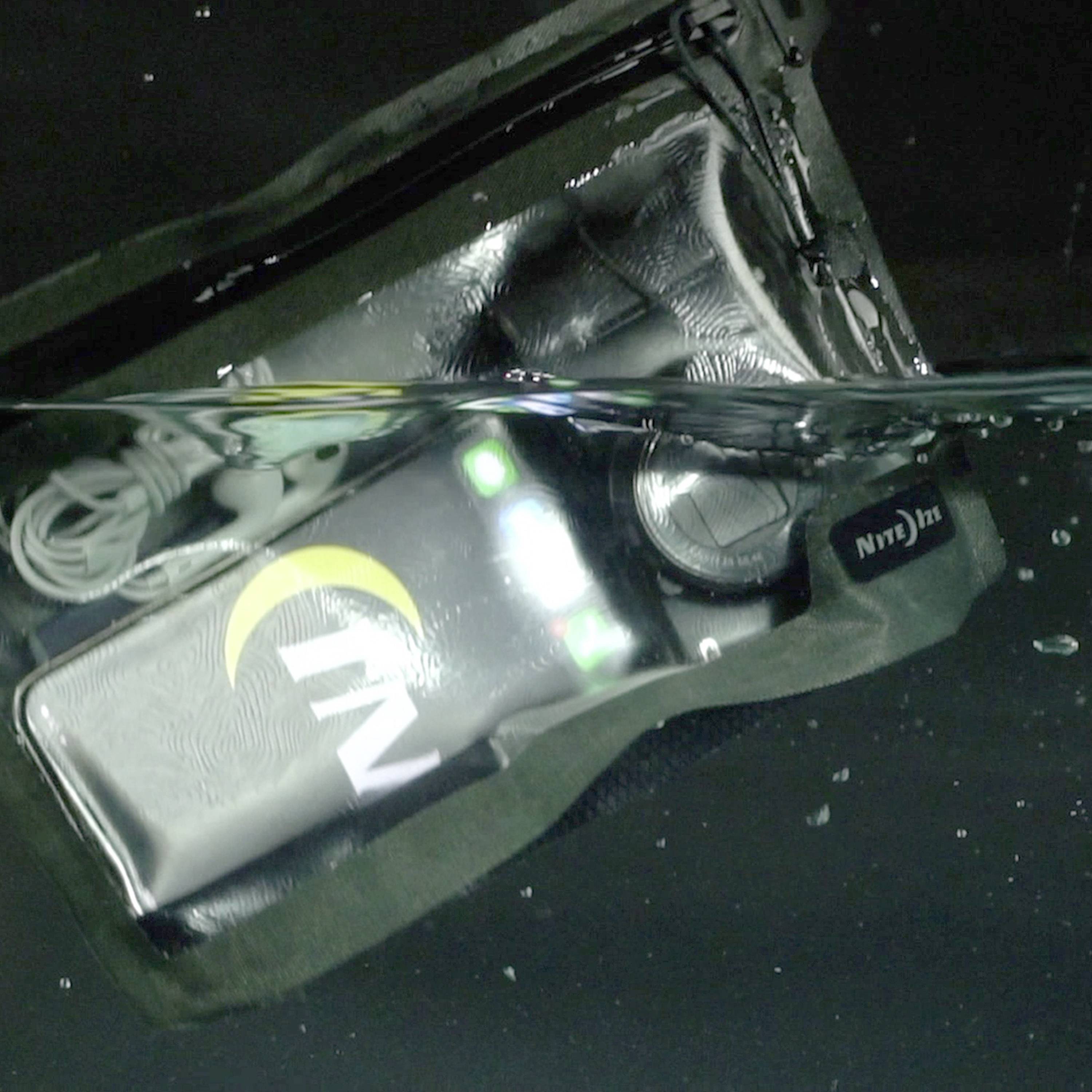 Un téléphone étanche avec un écran lumineux est placé dans un récipient rempli d'eau.