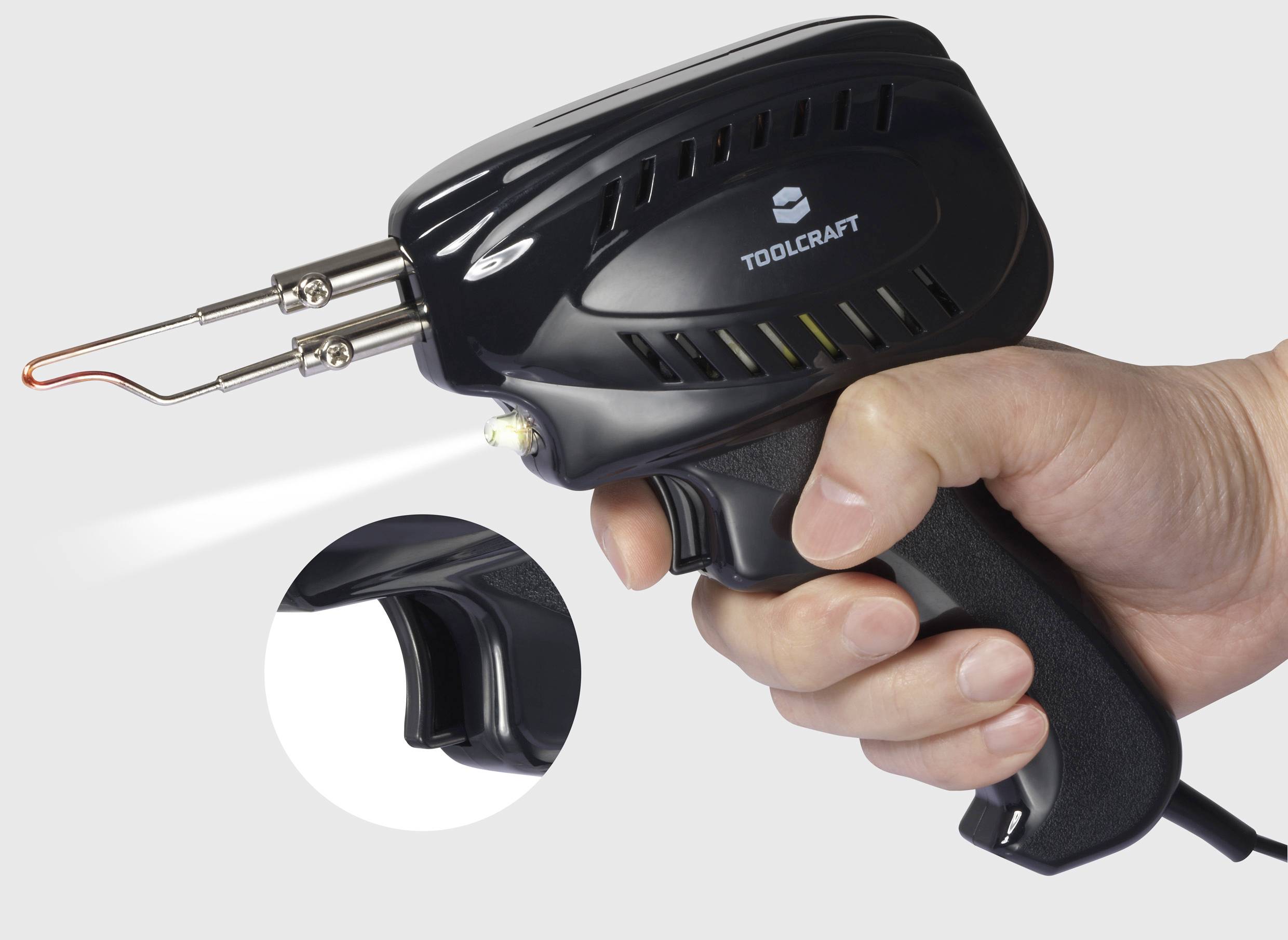 Une main tient un pistolet à souder électrique de la marque TOOLCRAFT. La pointe du pistolet est chaude et brille en rouge.