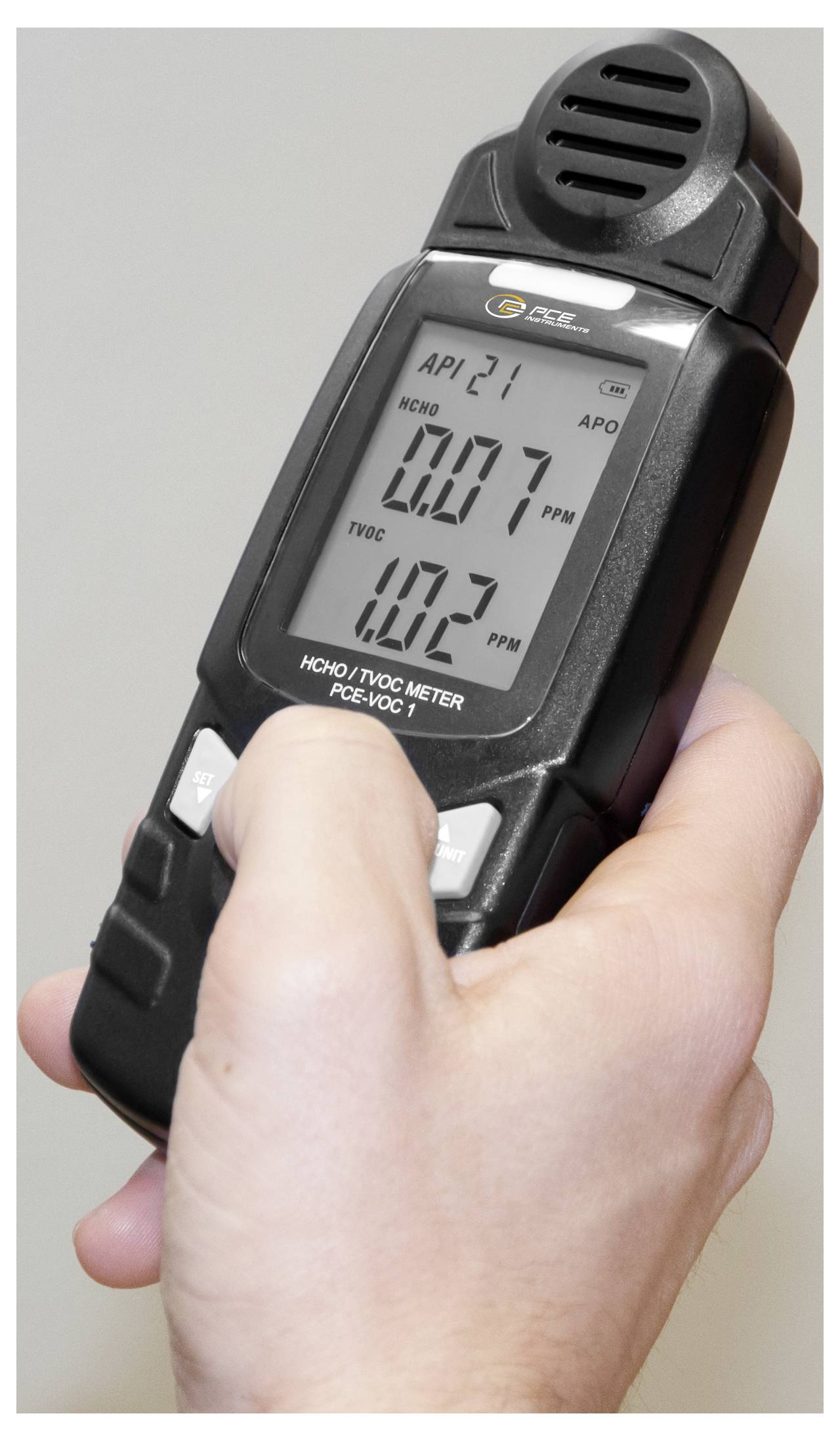 Appareil numérique portatif de mesure de la qualité de l'air montrant le formaldéhyde à 0,07 ppm et les COVT à 10,3 ppm dans la main d'une personne