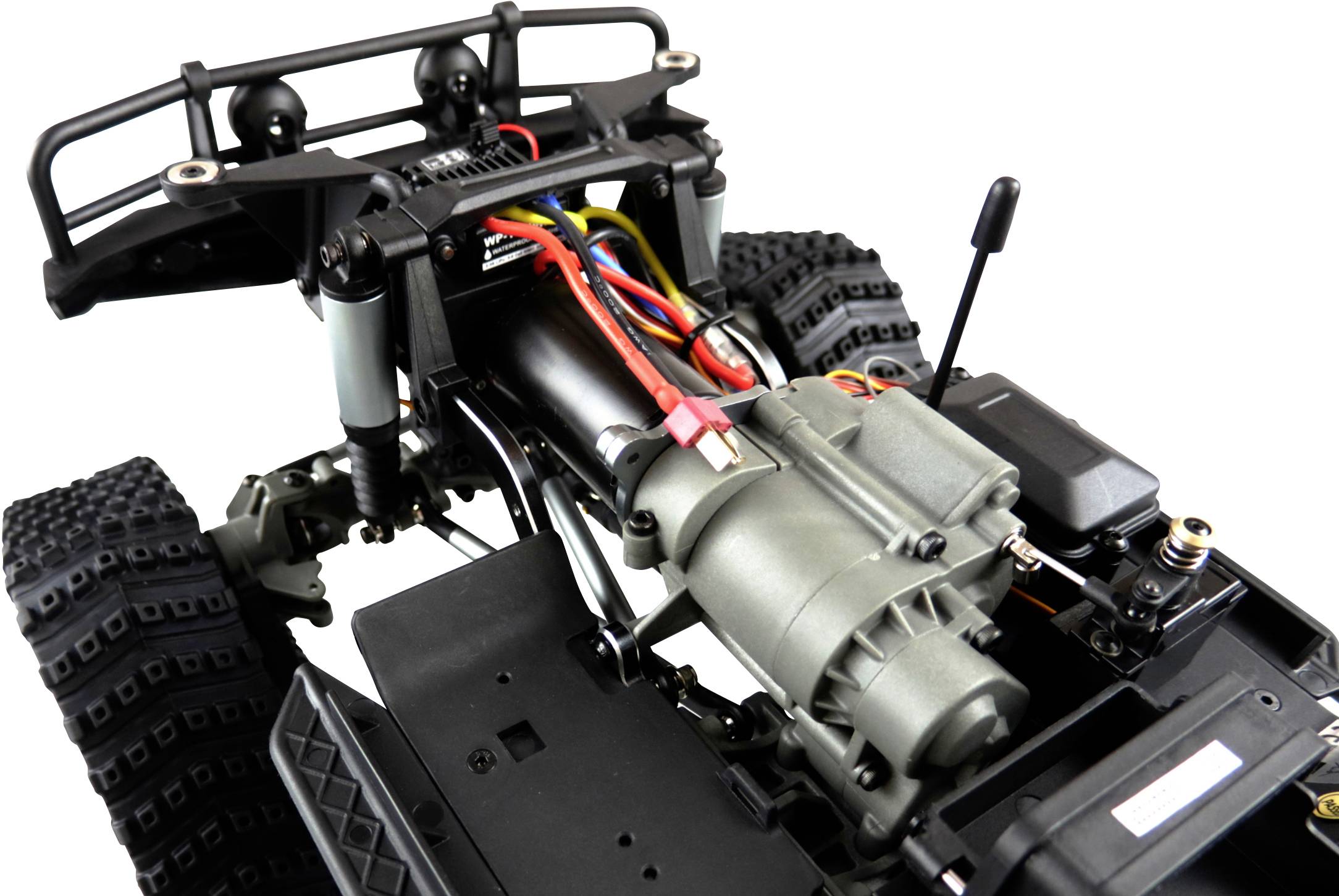 Gros plan d'une voiture télécommandée sans carrosserie. Le moteur, le câblage et des parties du châssis sont visibles.