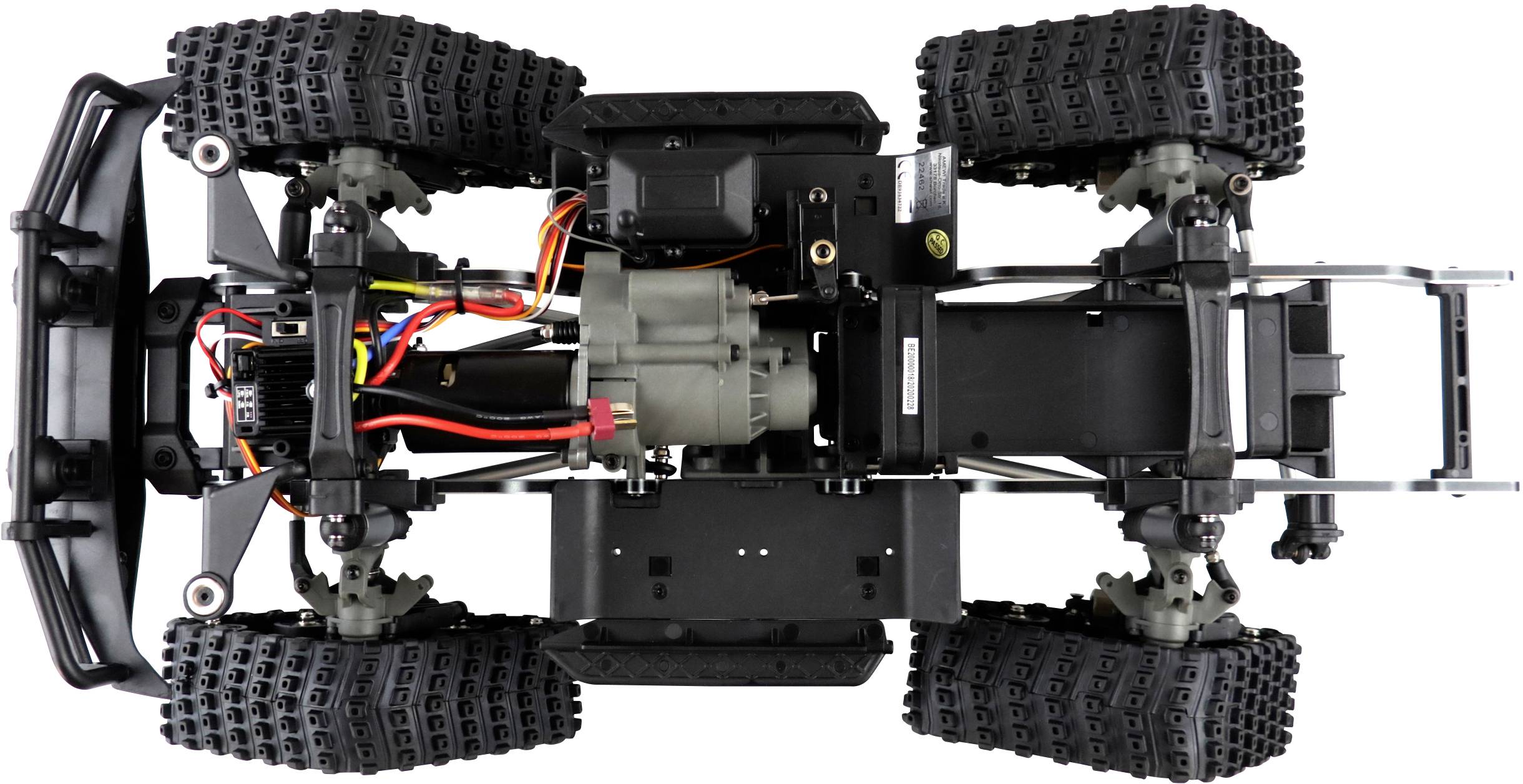 Une voiture télécommandée vue de dessous, avec un moteur à découvert, des câbles colorés et des pneus tout-terrain robustes.