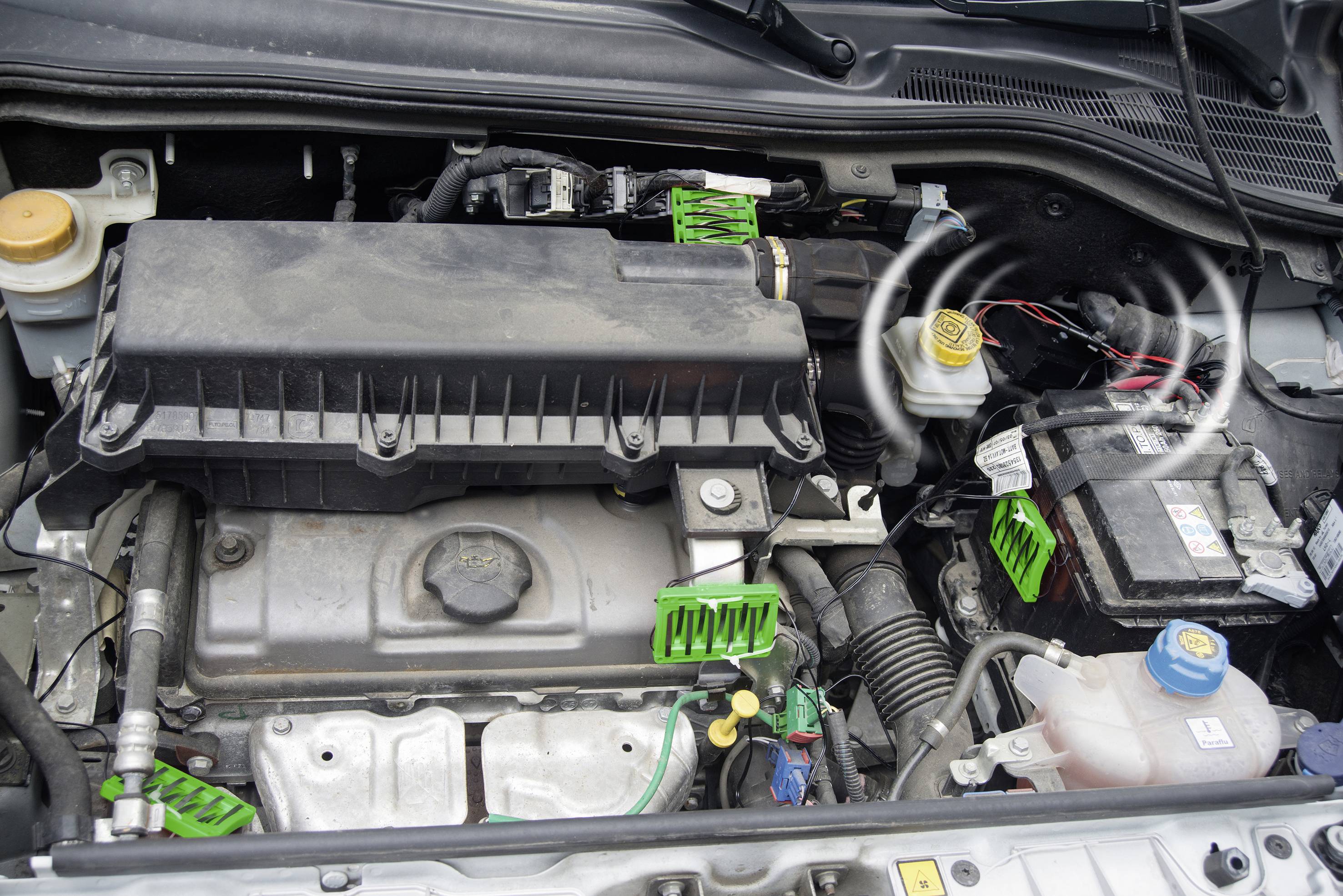 Un moteur de voiture ouvert avec des composants visibles, comprenant la batterie, le boîtier du filtre à air, le réservoir de liquide de refroidissement et des tuyaux.