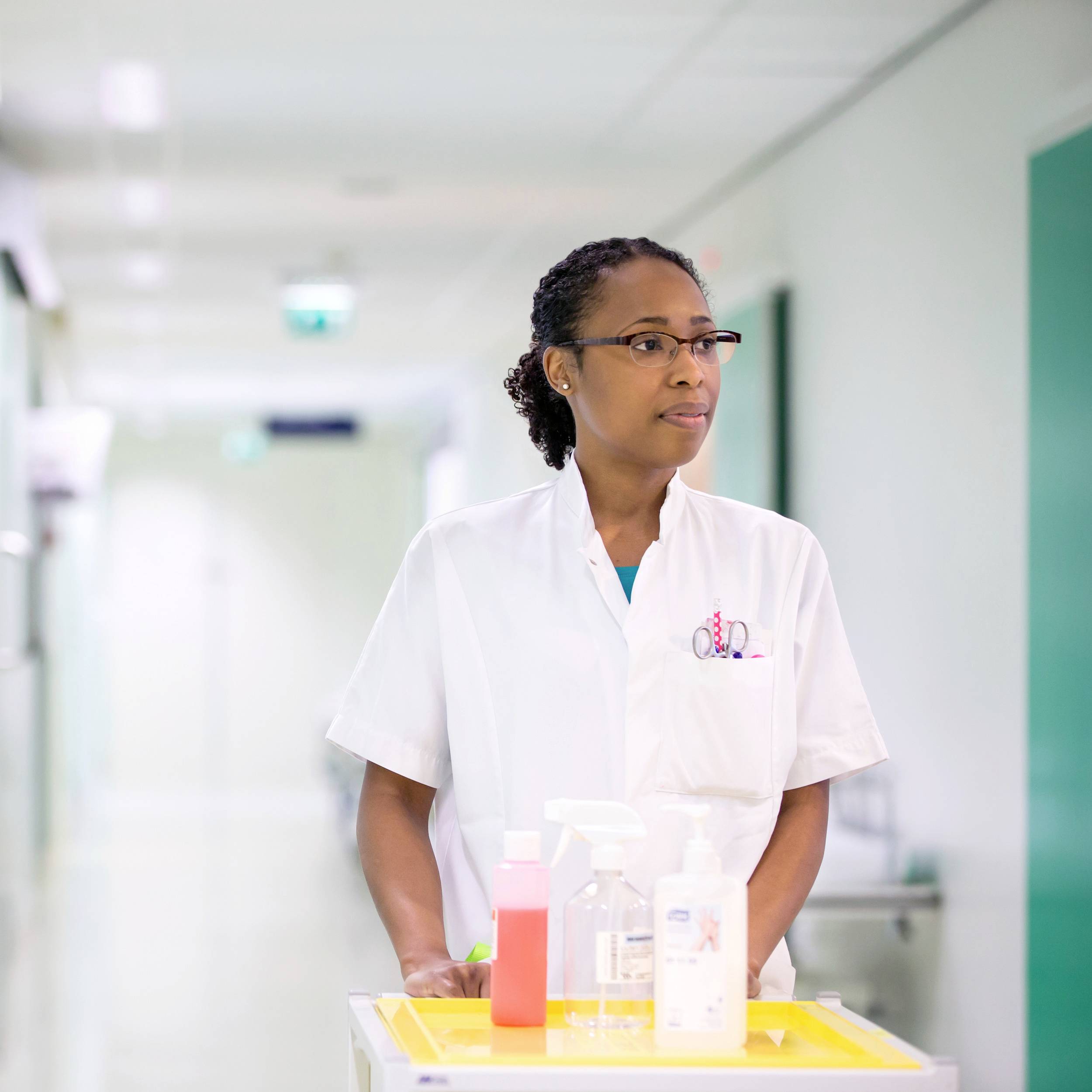 Une infirmière pousse un chariot chargé de désinfectants et de médicaments dans un couloir d'hôpital.