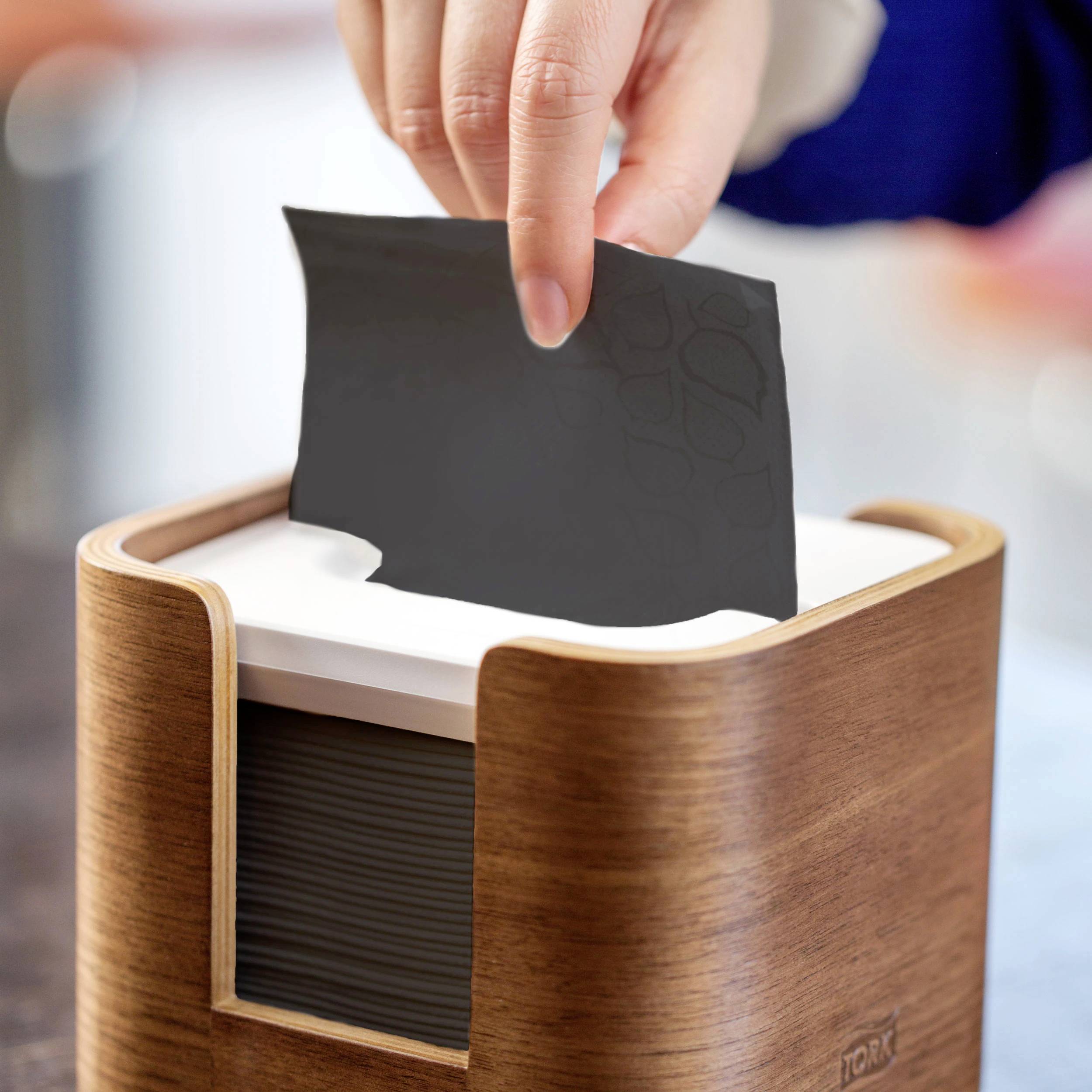 Une main retire un papier d'une boîte en bois.