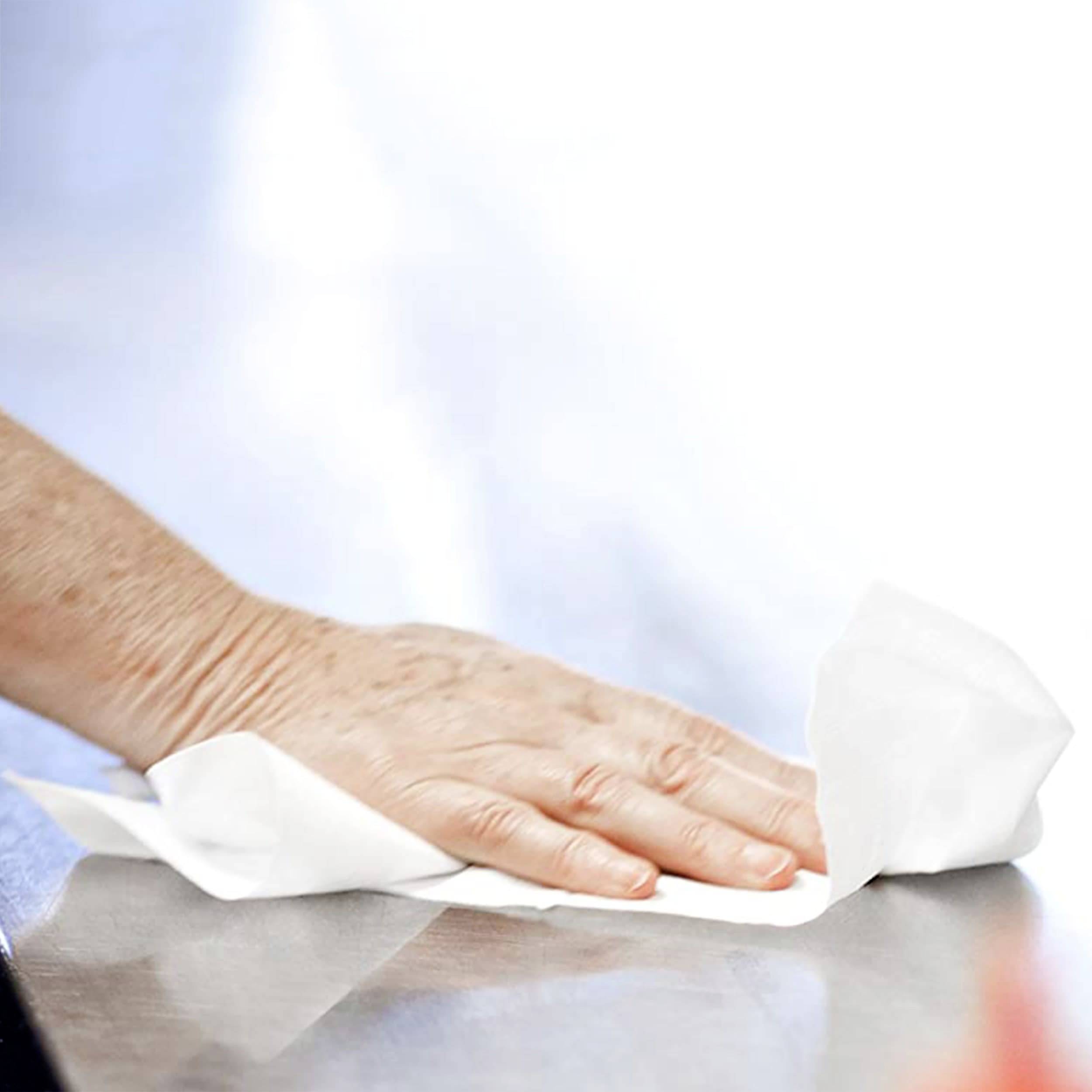 Une main essuie une surface métallique avec un chiffon blanc.