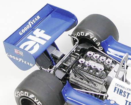 Une voiture de Formule 1 bleue avec les logos 'Goodyear' et 'elf' sur l'aileron arrière. Le moteur visible révèle une technique complexe.