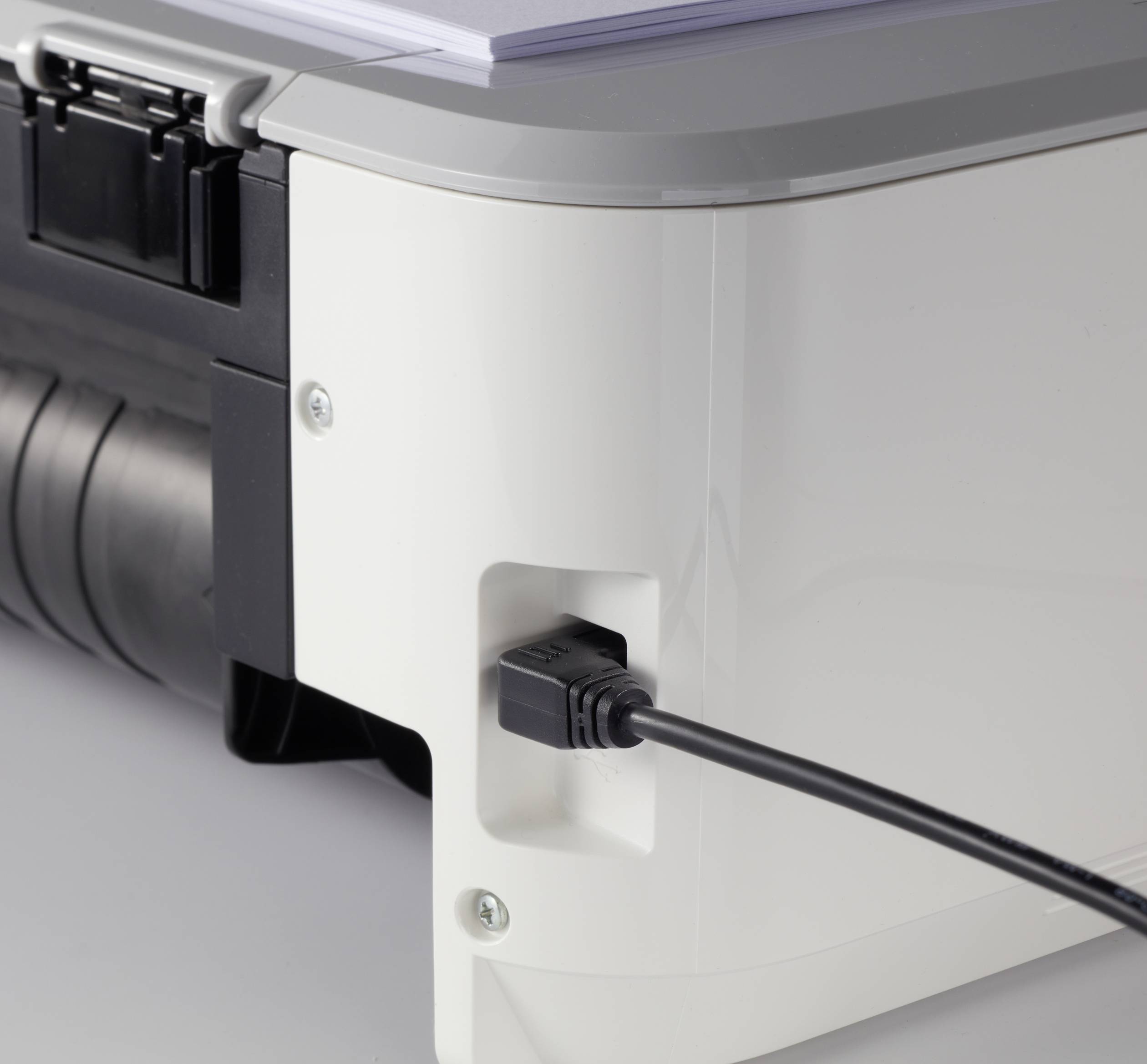 Une imprimante avec un câble USB connecté sur le côté. Un paquet de papier est prêt à être imprimé sur le dessus.