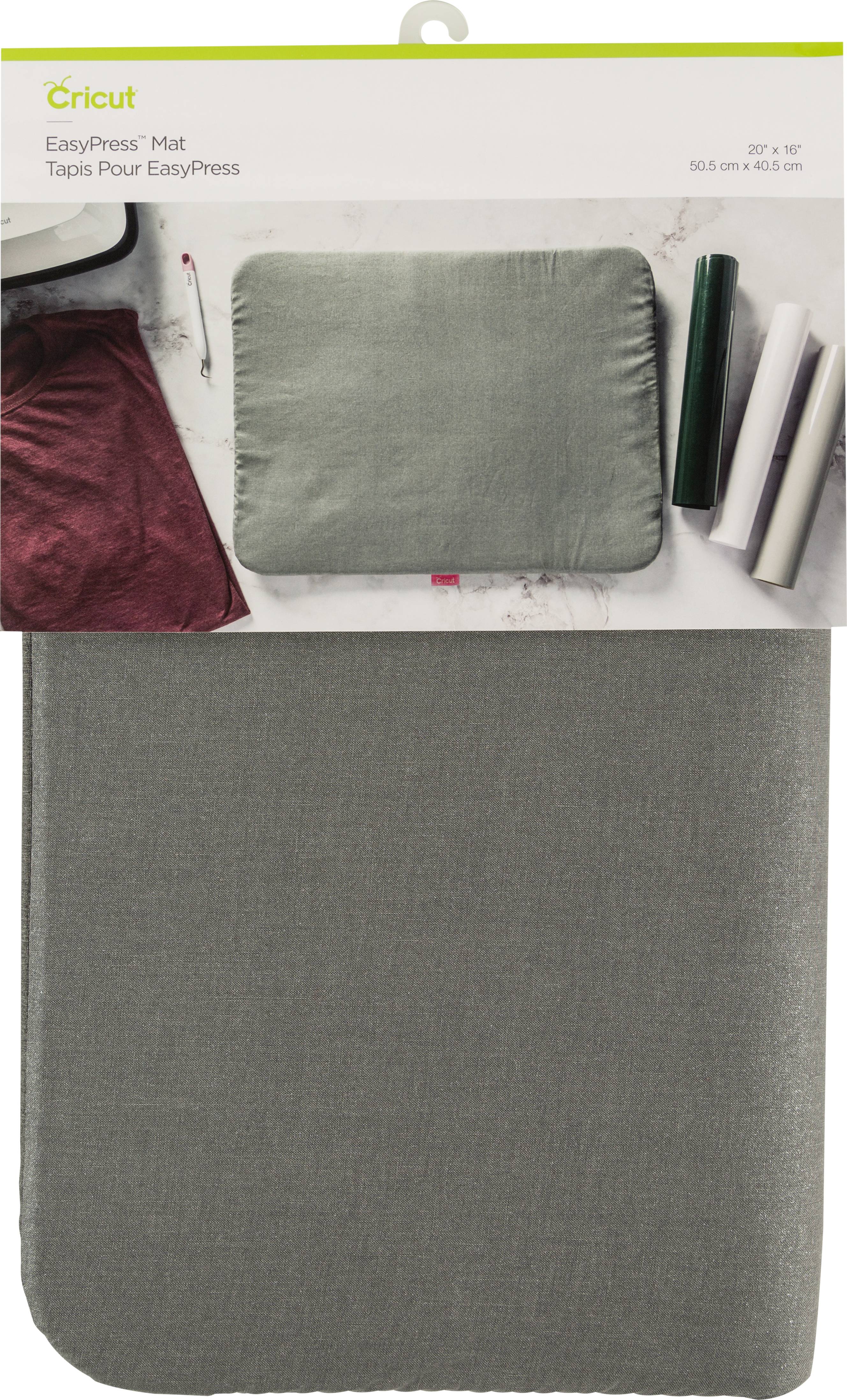 Presse EasyPress de Cricut en gris, présentée dans son emballage. Des textiles et des rouleaux sont disposés sur une table à côté.