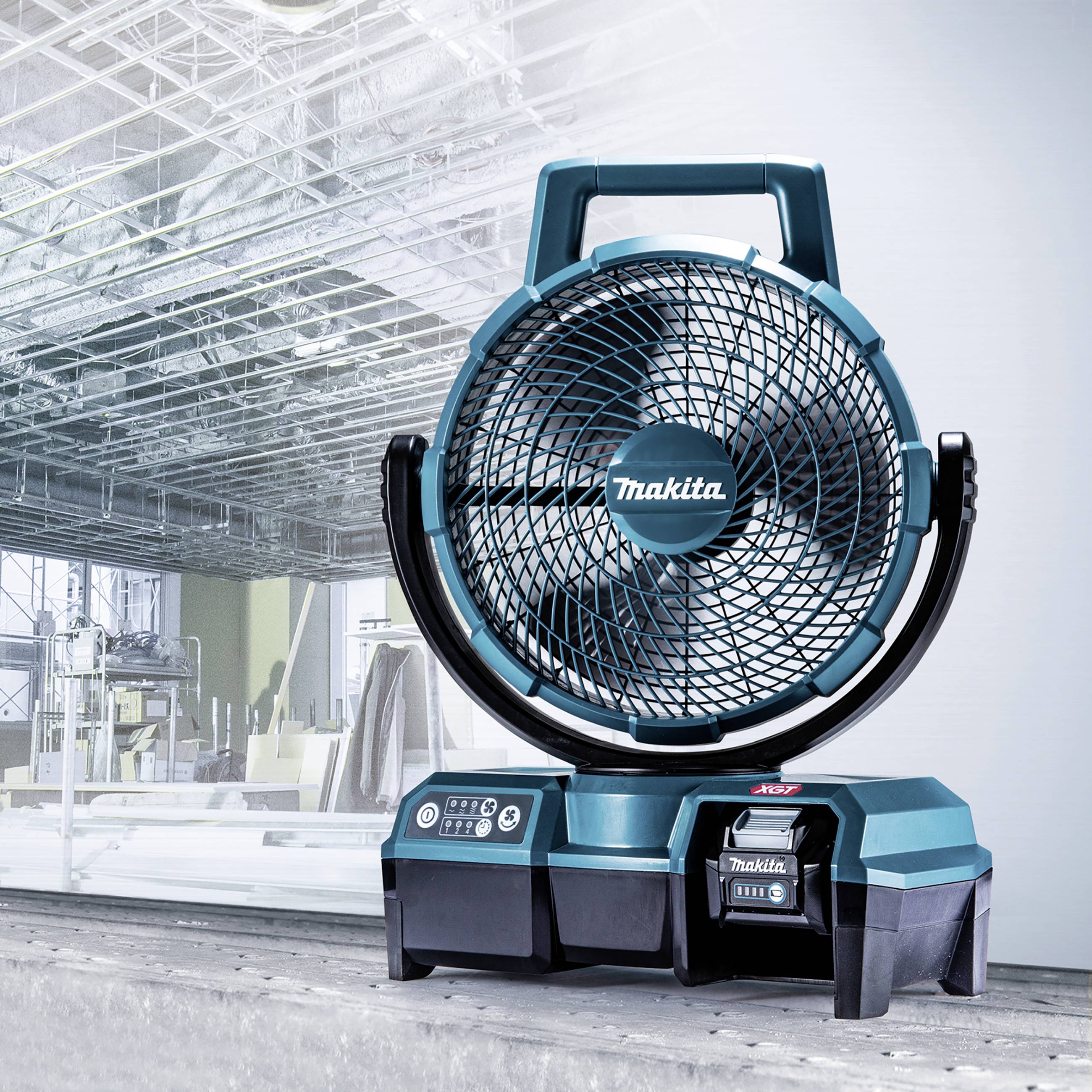 Un ventilateur de table bleu, alimenté par batterie, avec le nom de la marque à l'avant, placé sur une table devant un bâtiment de bureau moderne.